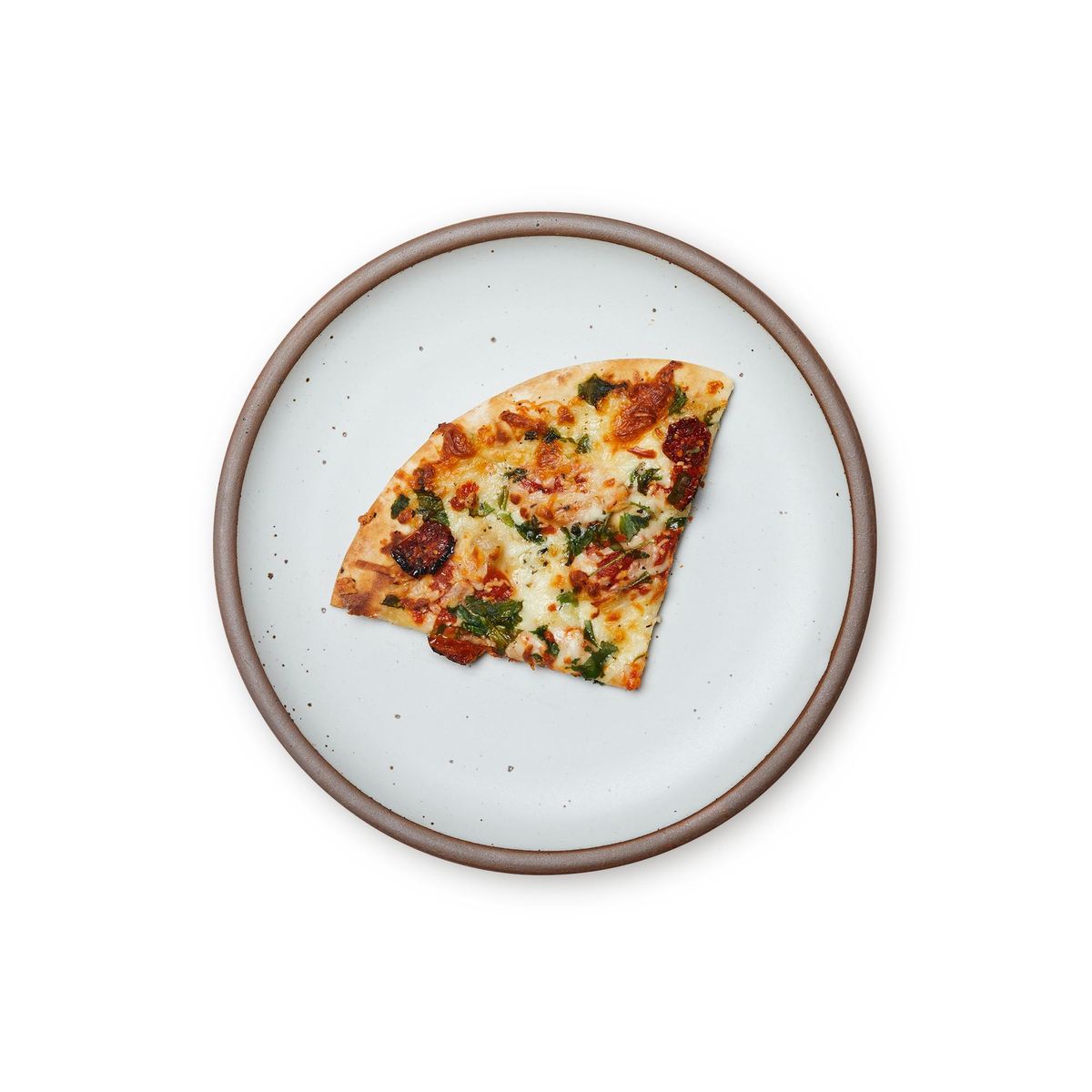 A slice of pizza on a dinner sized ceramic plate in a cool white color featuring iron speckles and an unglazed rim.
