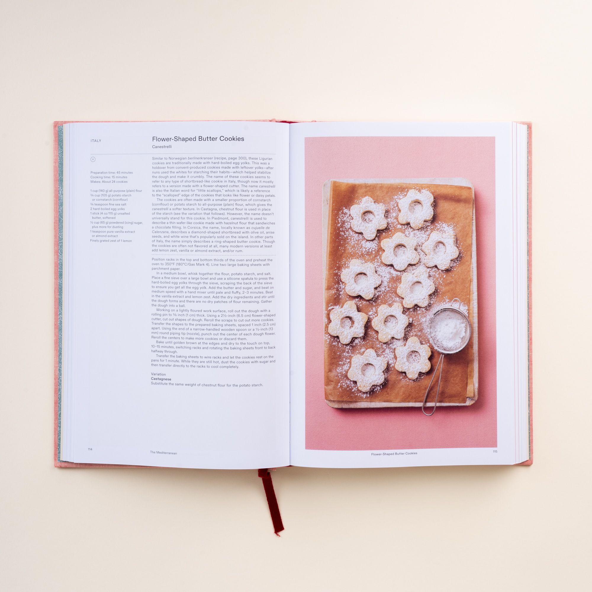 Open cookbook showing recipe text for flower-shaped butter cookies with photo of cookies dusted with powdered sugar.