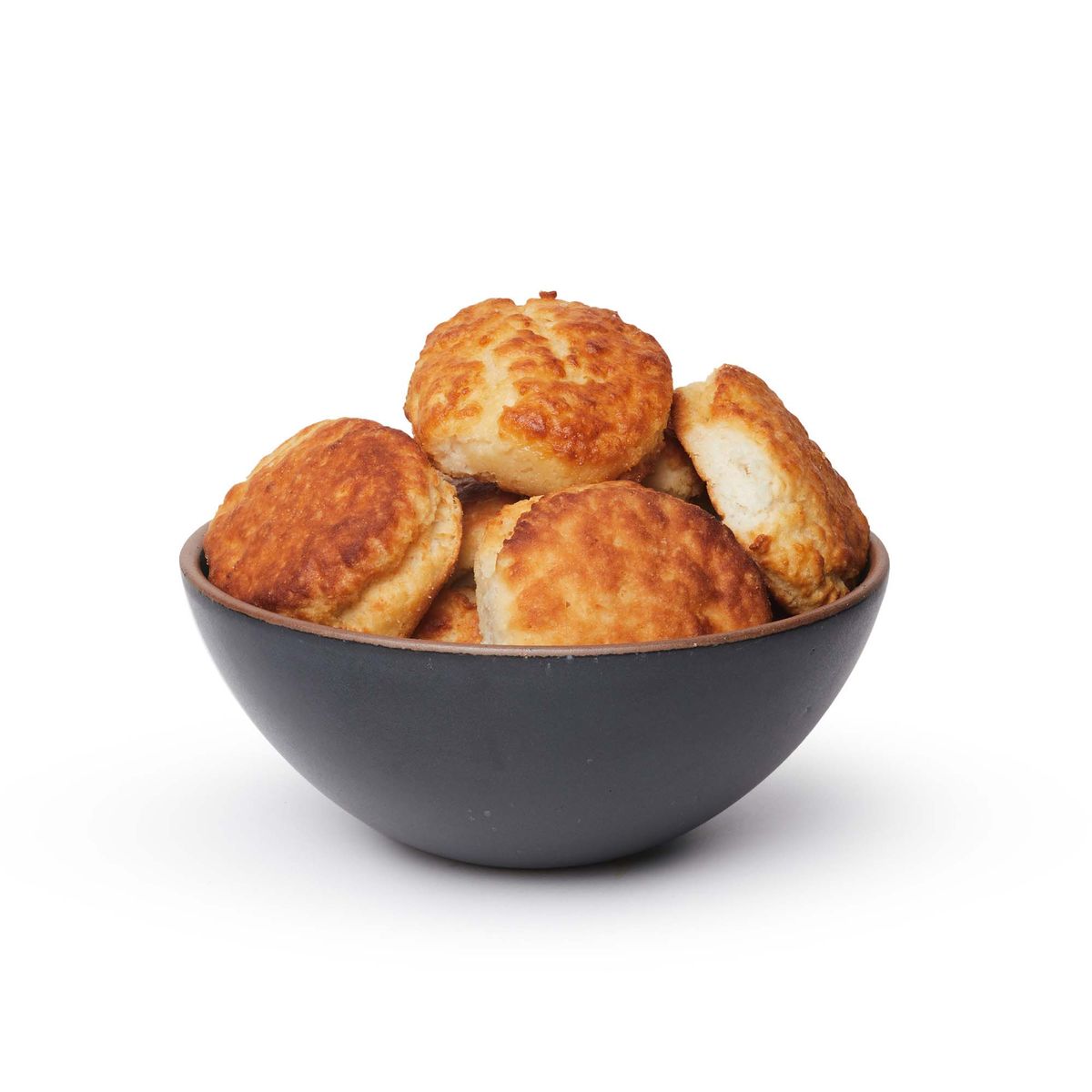 A large rounded ceramic bowl in a graphite black color featuring iron speckles and an unglazed rim, filled with biscuits