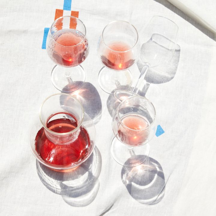 4 wine glasses and a carafe with rose on a blanket