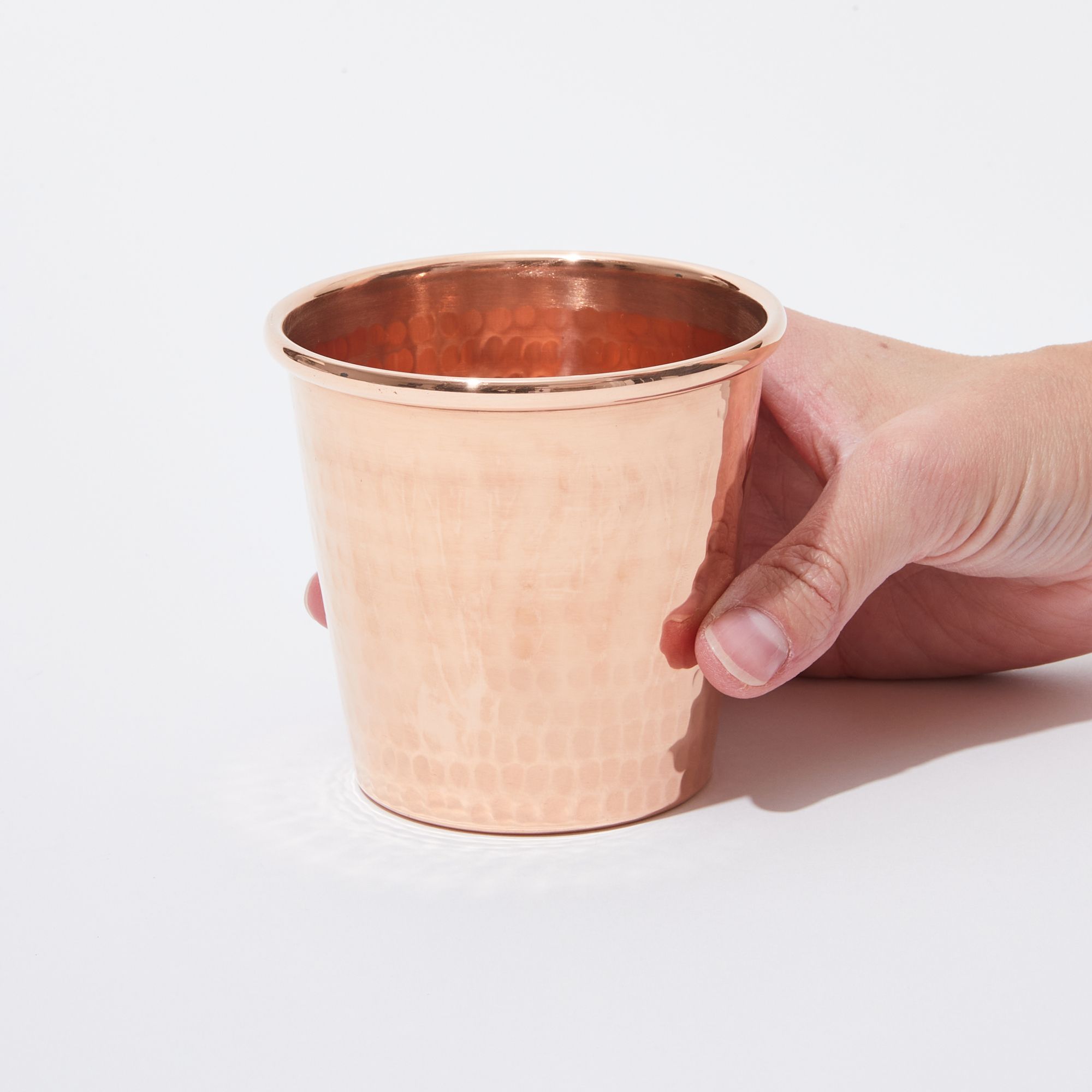 a hand holding a copper cup on the table