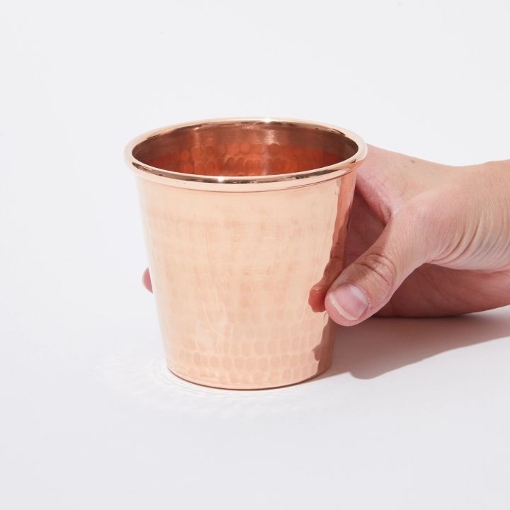 Hand holding a copper cup on a table