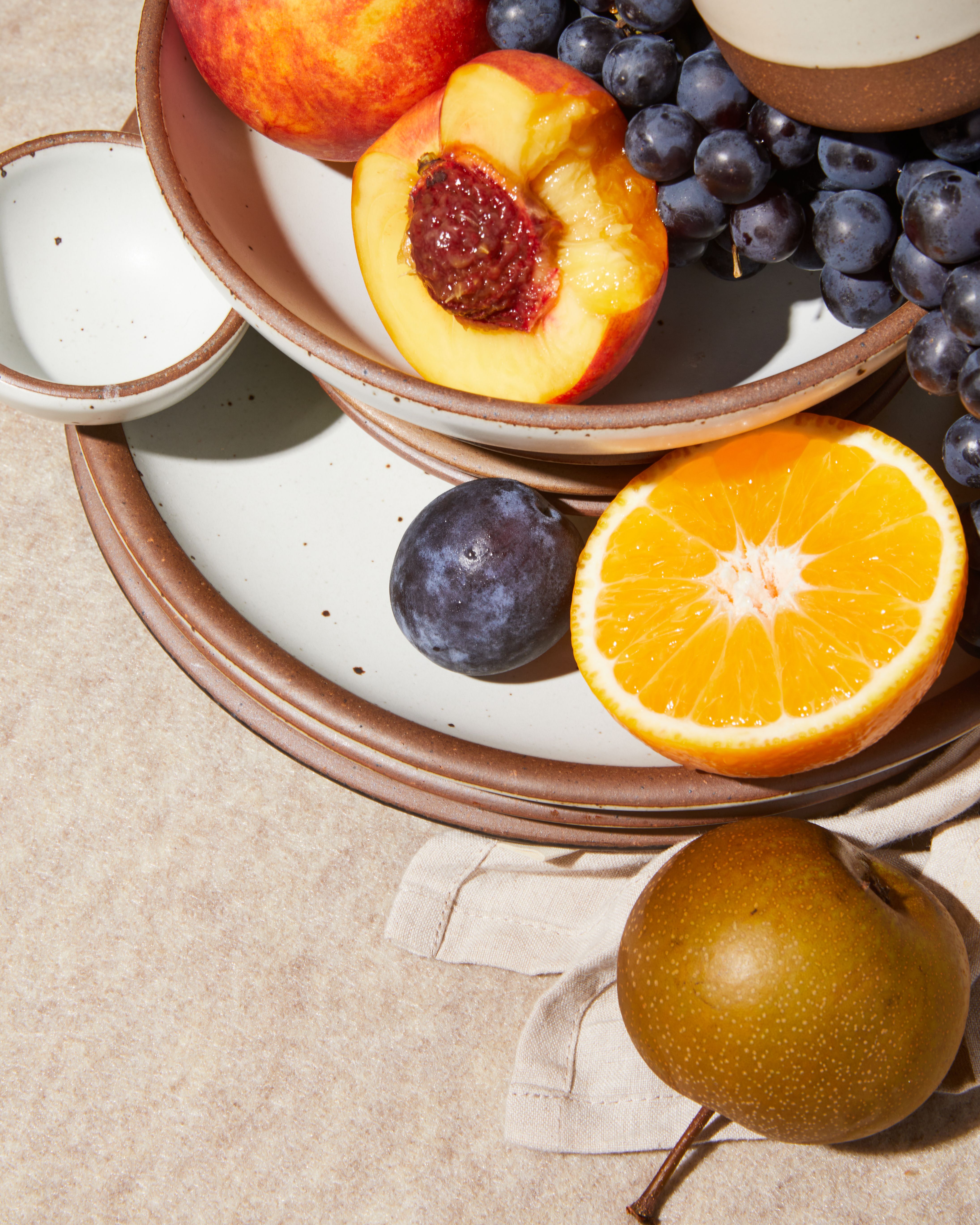 Oranges and grapes in an Amaro bowl on a light blue towel