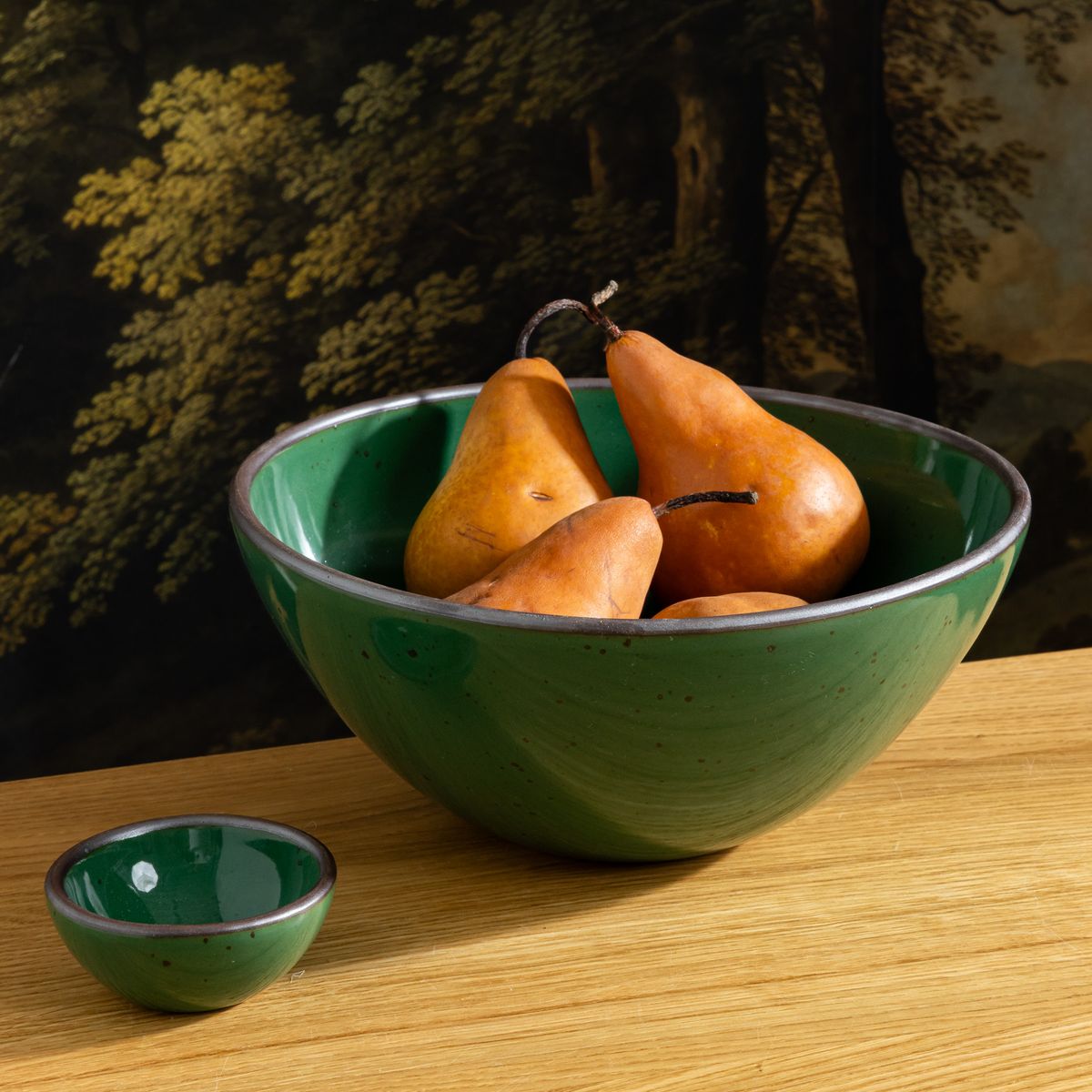 Glossy emerald green ceramic serving bowl with pears, paired with a small matching bowl on a wooden table.
