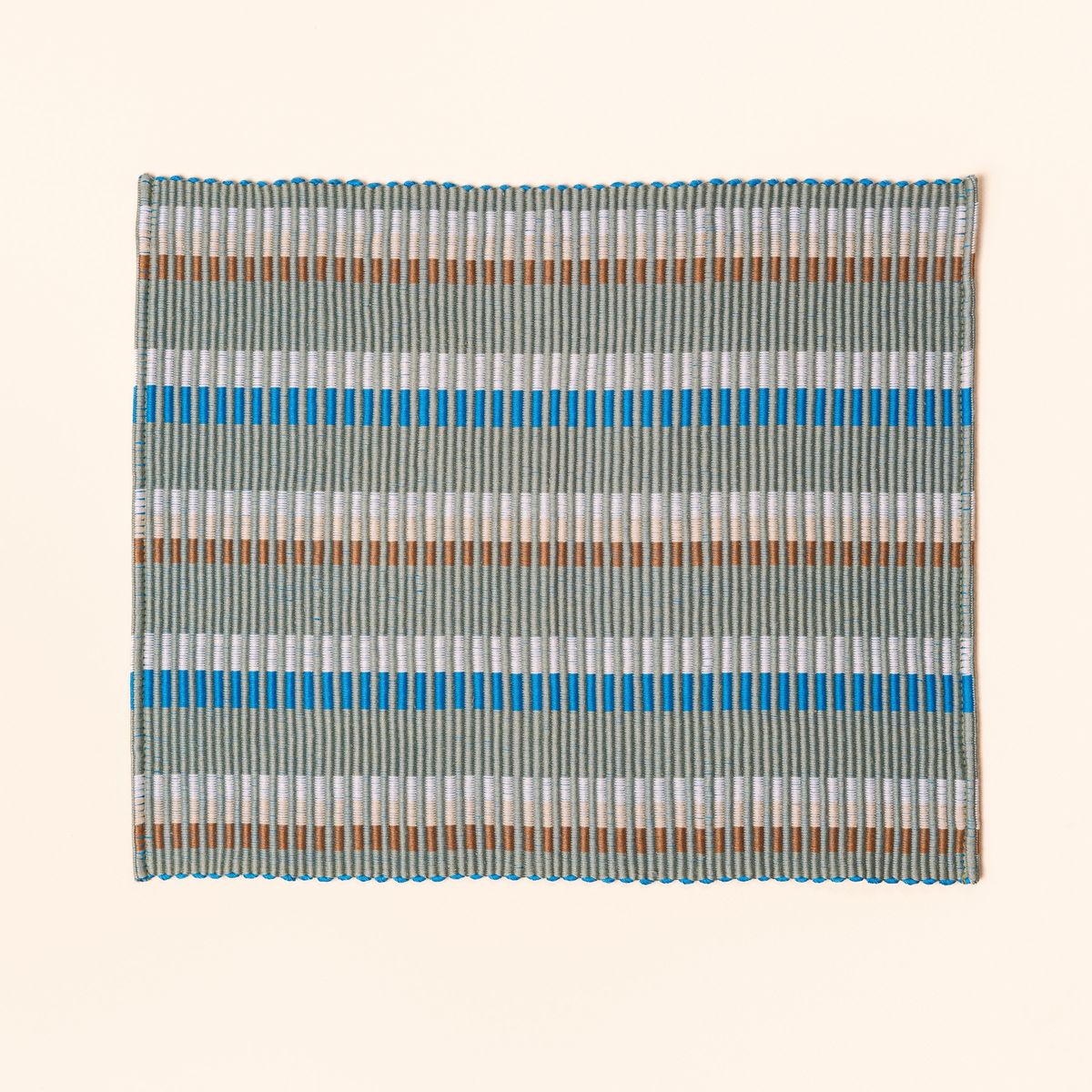 Rectangle placemat with offset stripe design that is hand woven in sage, blue, and orange colors
