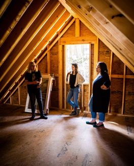Image of BeLoved's Amy Cantrell, East Fork Community Impact Manager Davia and East Fork Copywriter, Jasmin, standing in a partially finished home