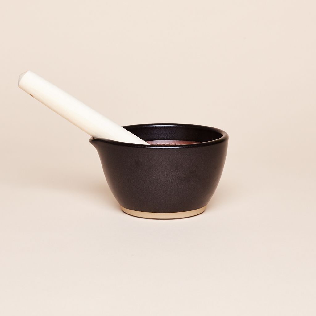 Black mortar has a white pestle slanting out to the left side