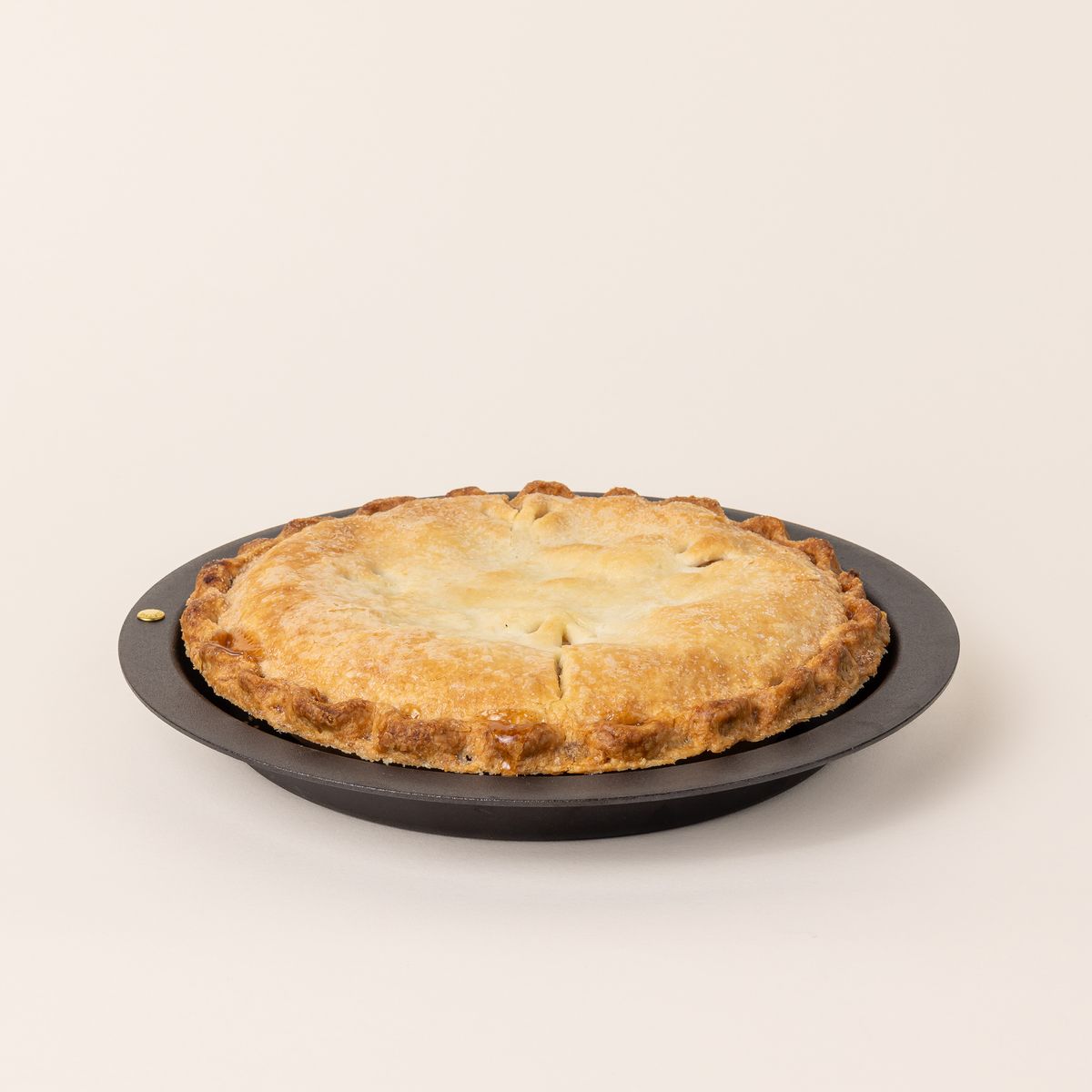 A full cooked pie in a simple iron pie plate with a wide rim and shallow body