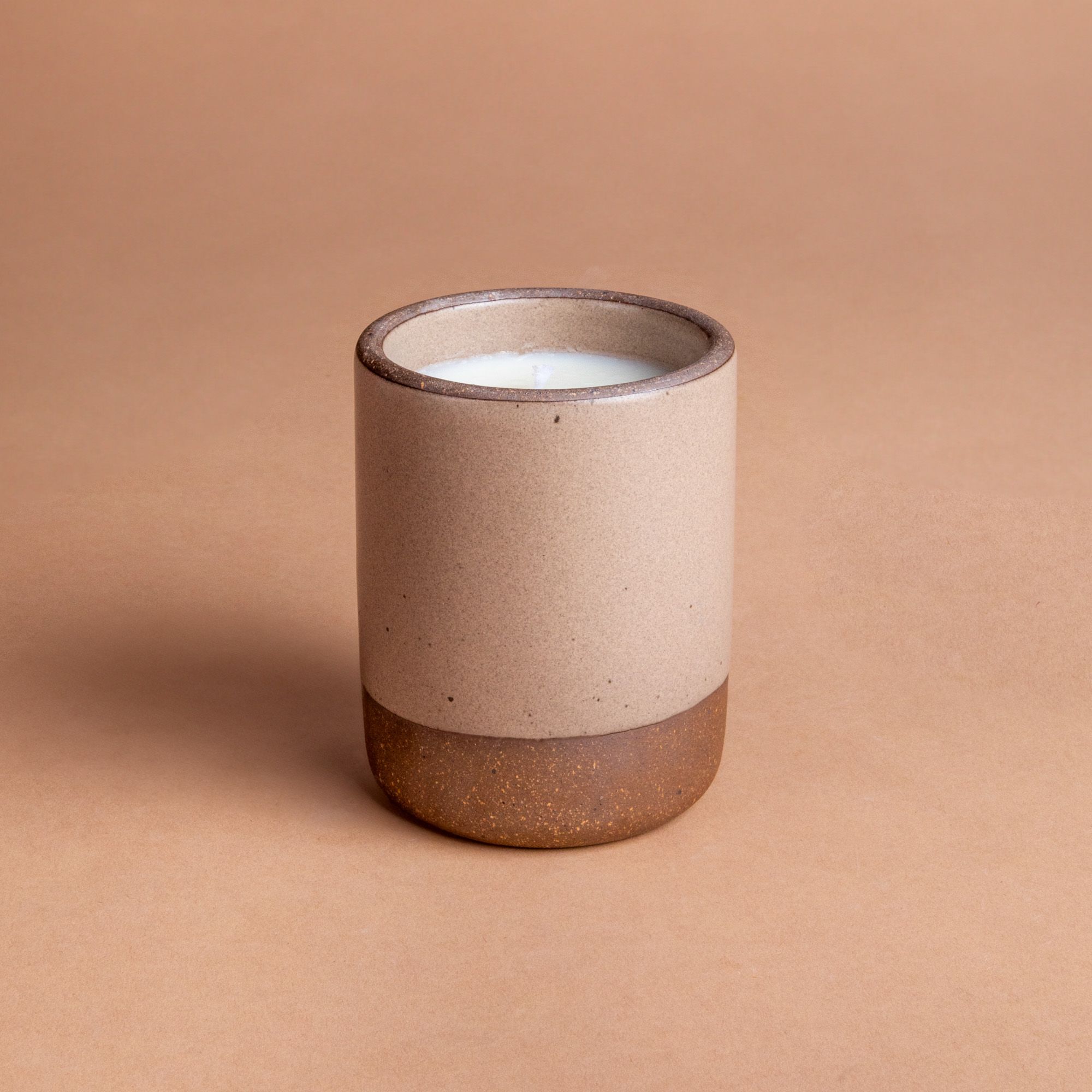 Large ceramic vessel in a warm pale brown color with candle inside.