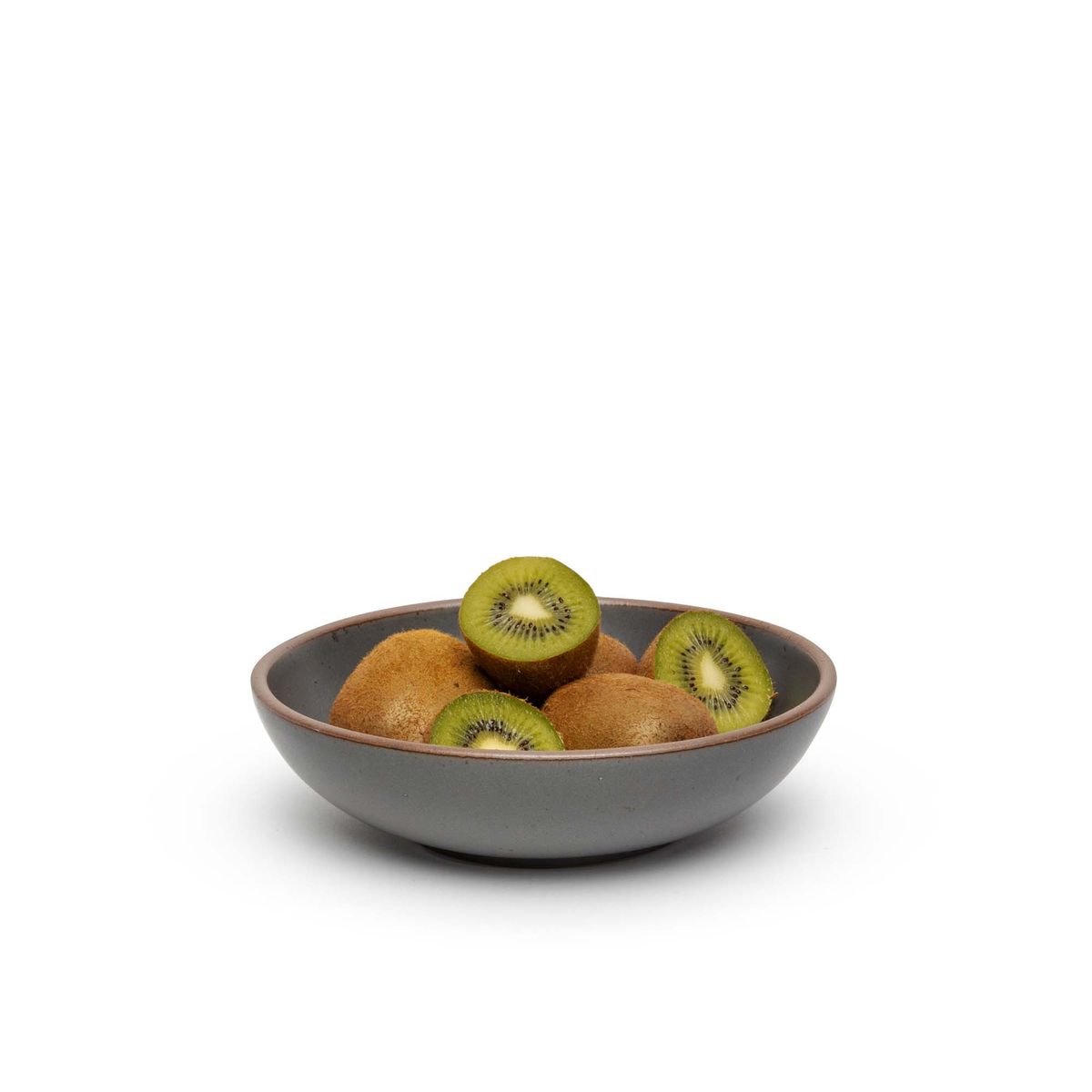 A dinner-sized shallow ceramic bowl in a cool, medium grey color featuring iron speckles and an unglazed rim, filled with sliced kiwi