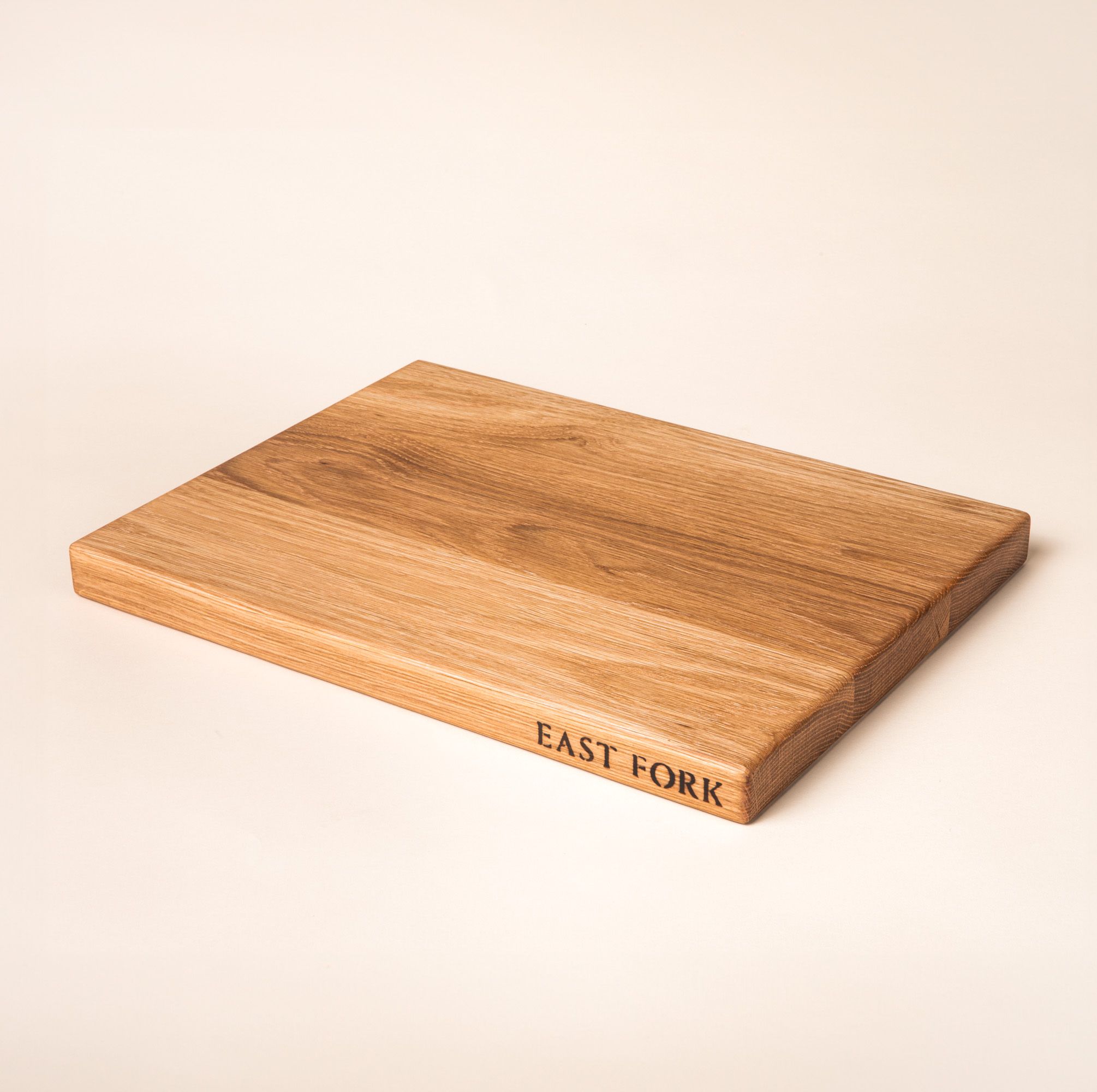 A medium rectangular white oak cutting board on its side with an engraving on the edge that reads 'East Fork'