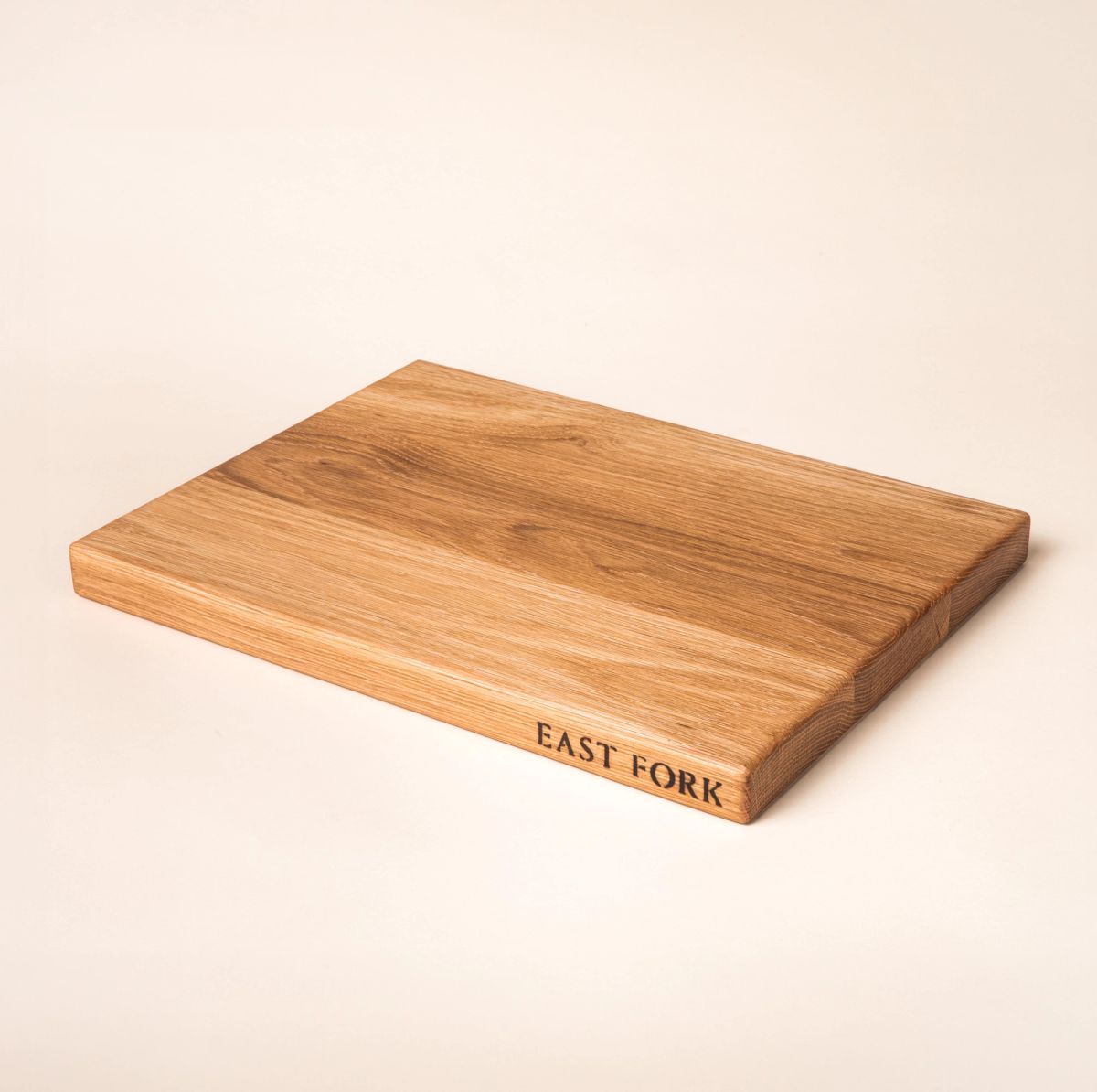 A medium rectangular white oak cutting board on its side with an engraving on the edge that reads 'East Fork'