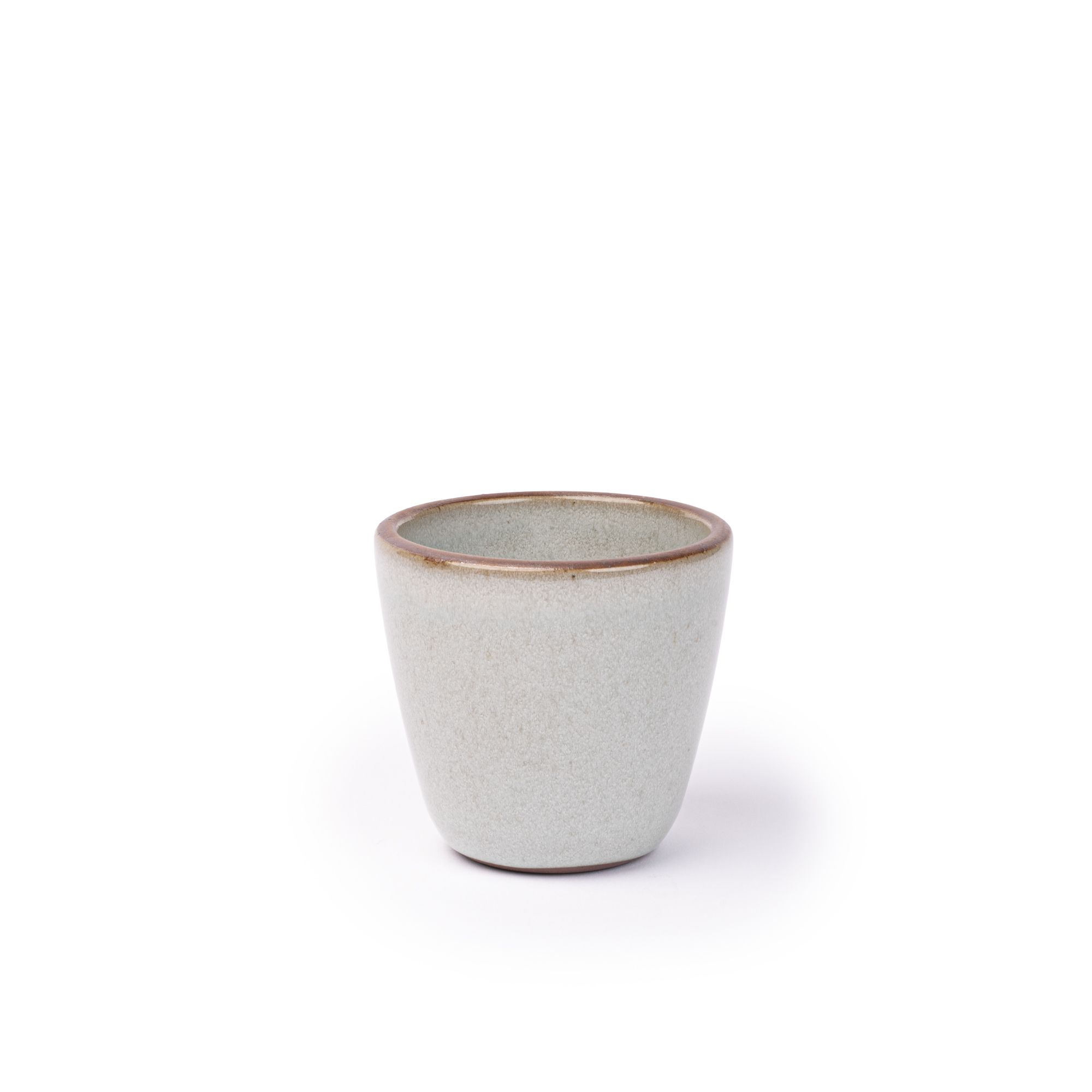 A short cup that tapers out to get wider at the top in a reflective icy off-white color featuring iron speckles