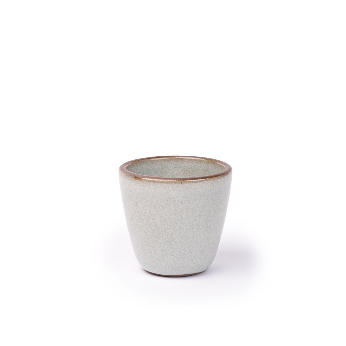 A short cup that tapers out to get wider at the top in a reflective icy off-white color featuring iron speckles