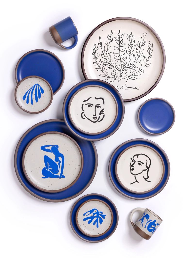 Ceramic plates and mugs with decals of Henri Matisse's artworks along with a cobalt blue plates and mugs on white background.