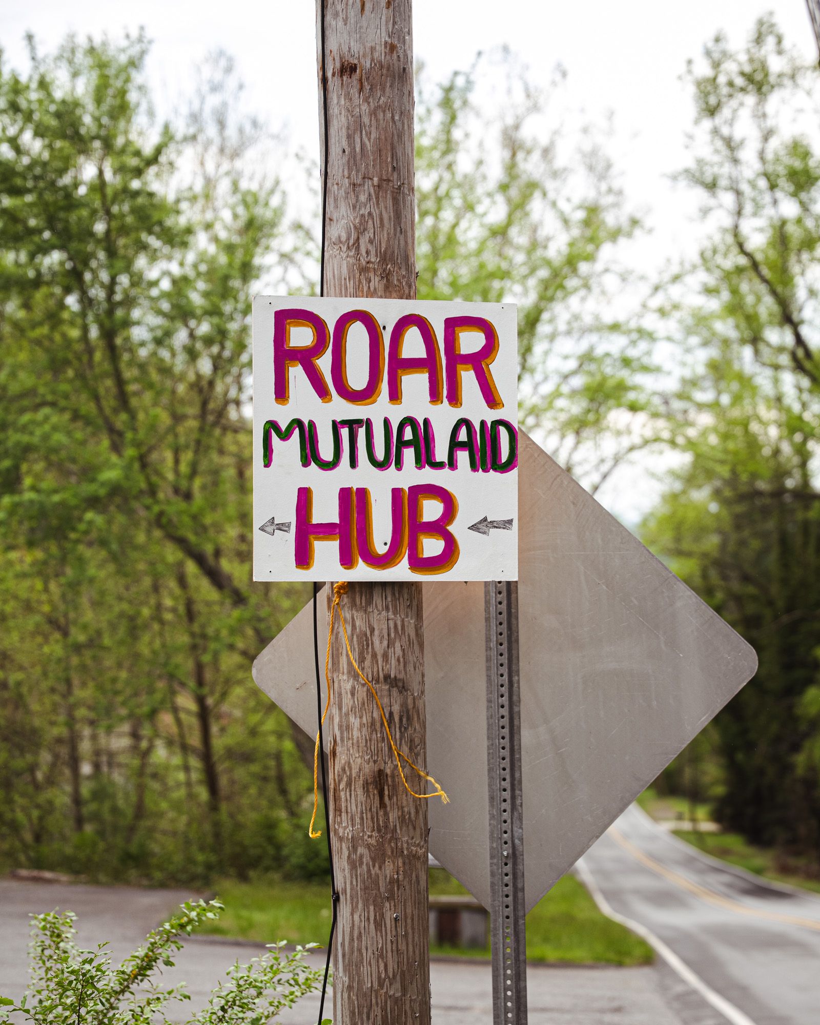 Outside, a street sign that reads 'ROAR Mutual Aid Hub'