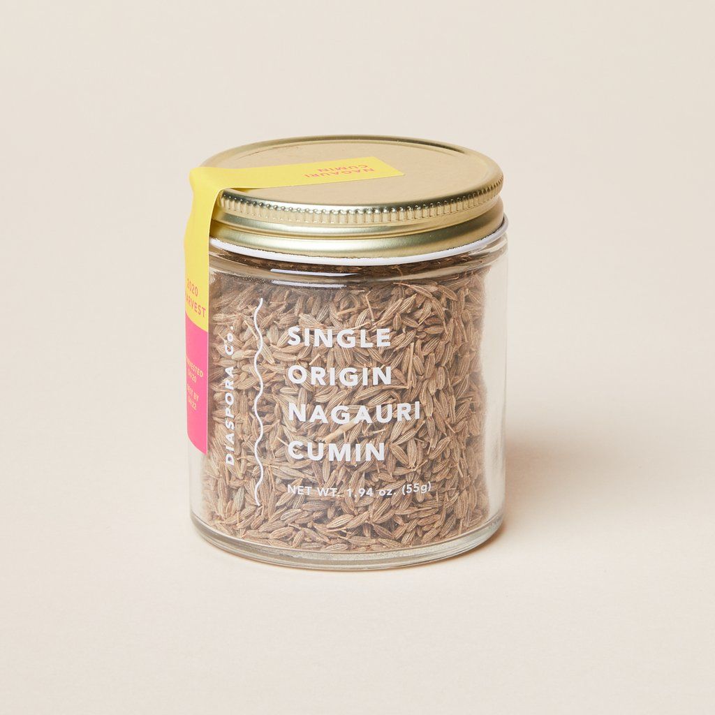 Glass jar with gold lid that contains whole cumin spice
