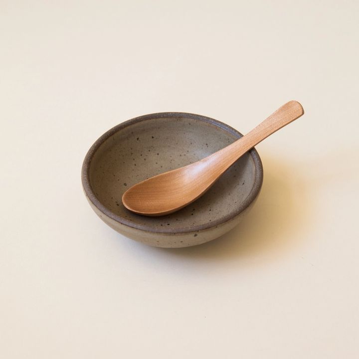 Wooden soup spoon resting in a morel-colored bowel