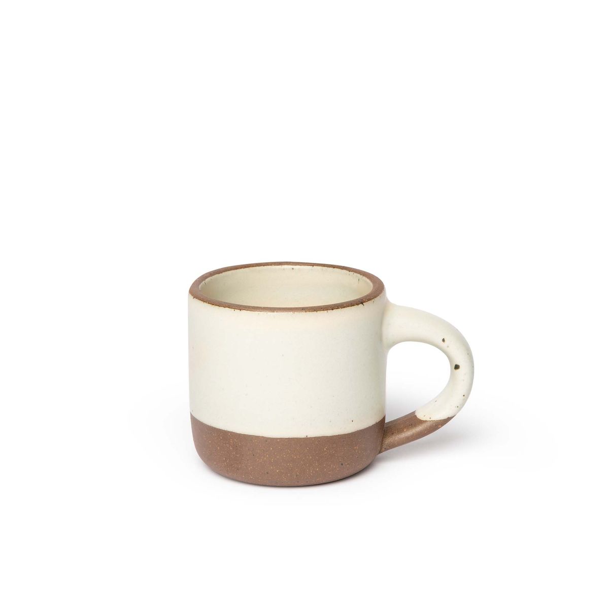A small sized ceramic mug with handle in a warm, tan-toned, off-white glaze featuring iron speckles and unglazed rim and bottom base.
