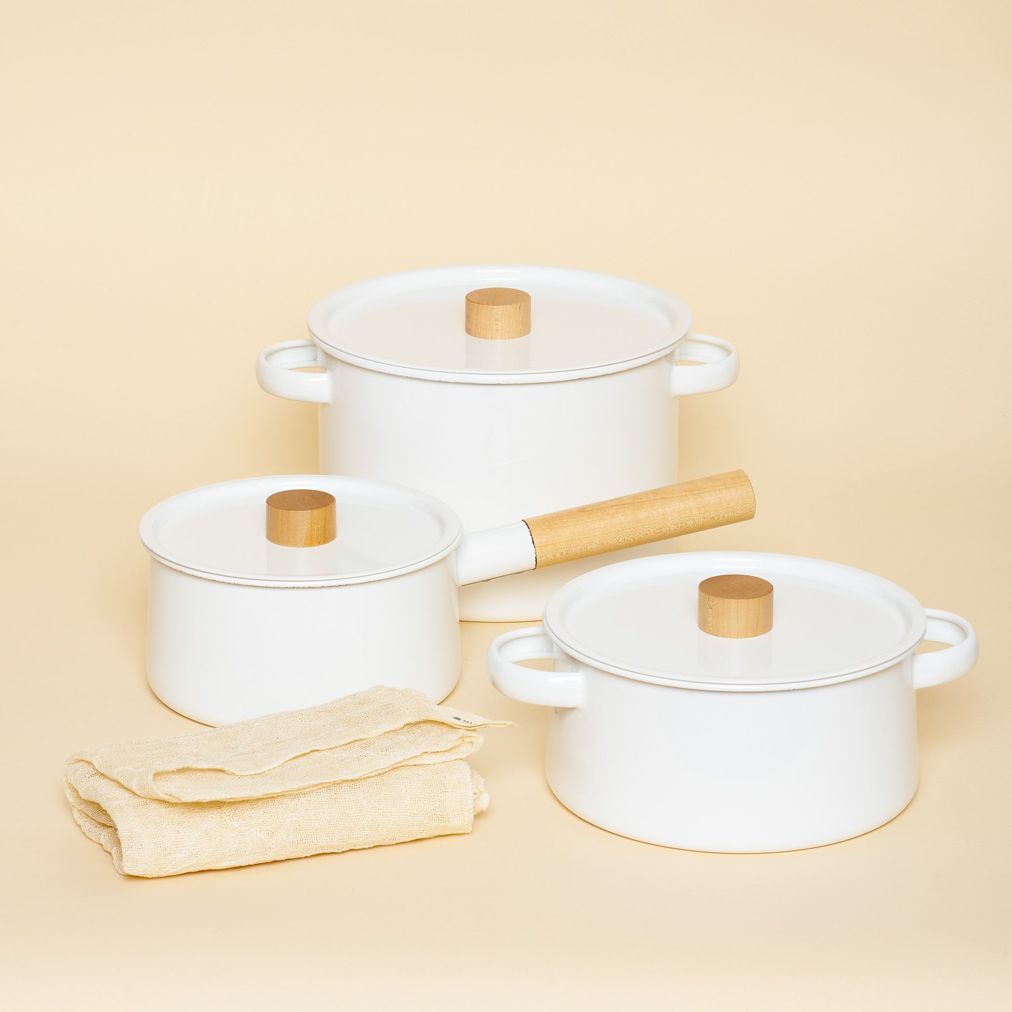 A set of three white enamel cookware pots and pans