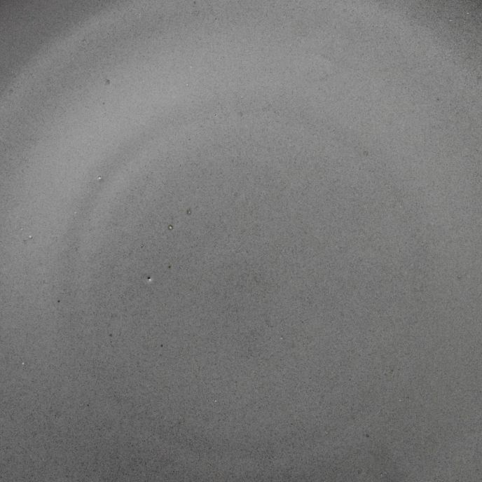 A closeup of a ceramic plate in a charcoal grey color with subtle iron speckles throughout