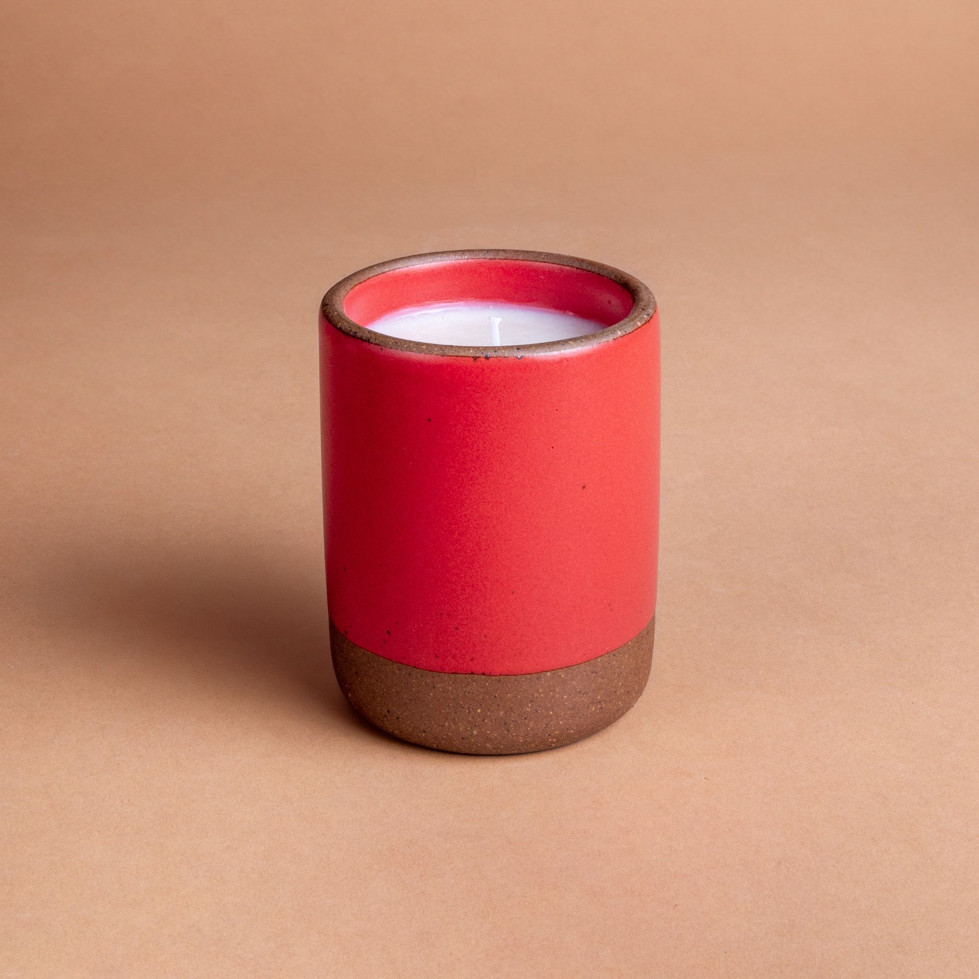 Large ceramic vessel in a bold red color with candle inside.