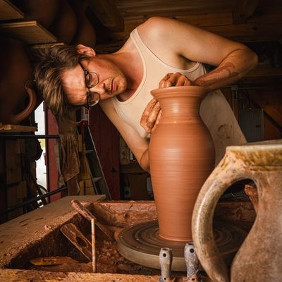 John forming a pitcher on a potter's wheel in his studio.