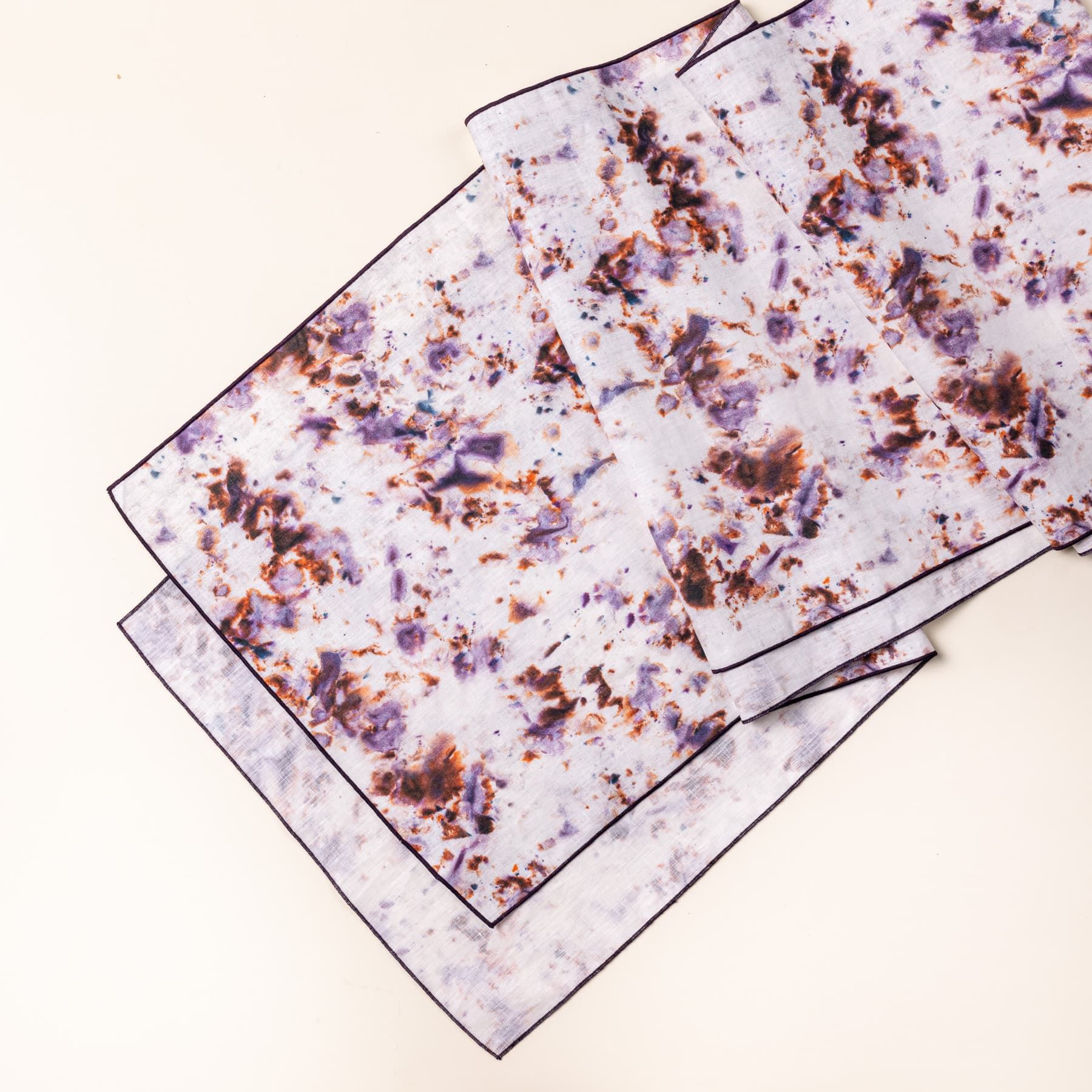 A table runner with a marble pattern featuring pink, purple, orange and white colors folded artfully 