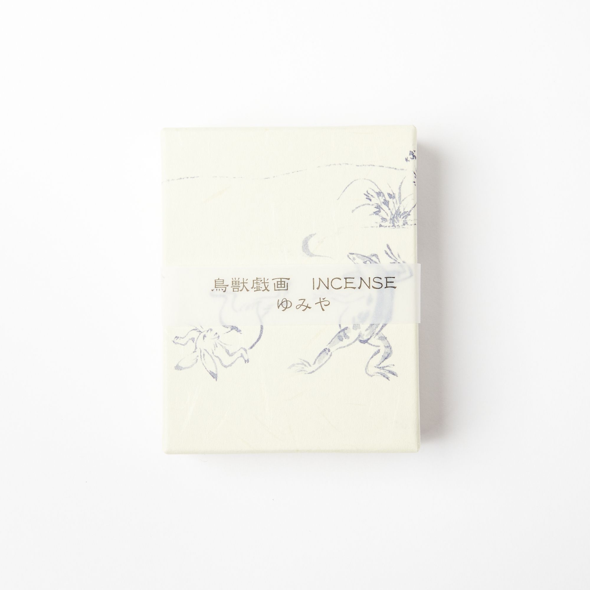 A cream box with a transparent paper band with Japanese writing and the word "Incense". The box also has soft blue sparse illustrations of greenery and animals.