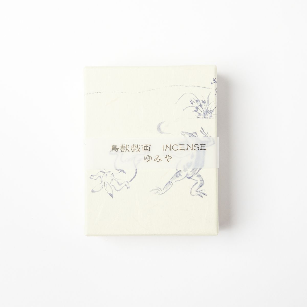 A cream box with a transparent paper band with Japanese writing and the word "Incense". The box also has soft blue sparse illustrations of greenery and animals.