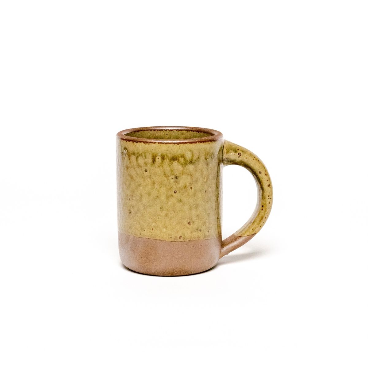 A medium sized ceramic mug with handle in an earthy green and brown color featuring iron speckles and unglazed rim and bottom base.