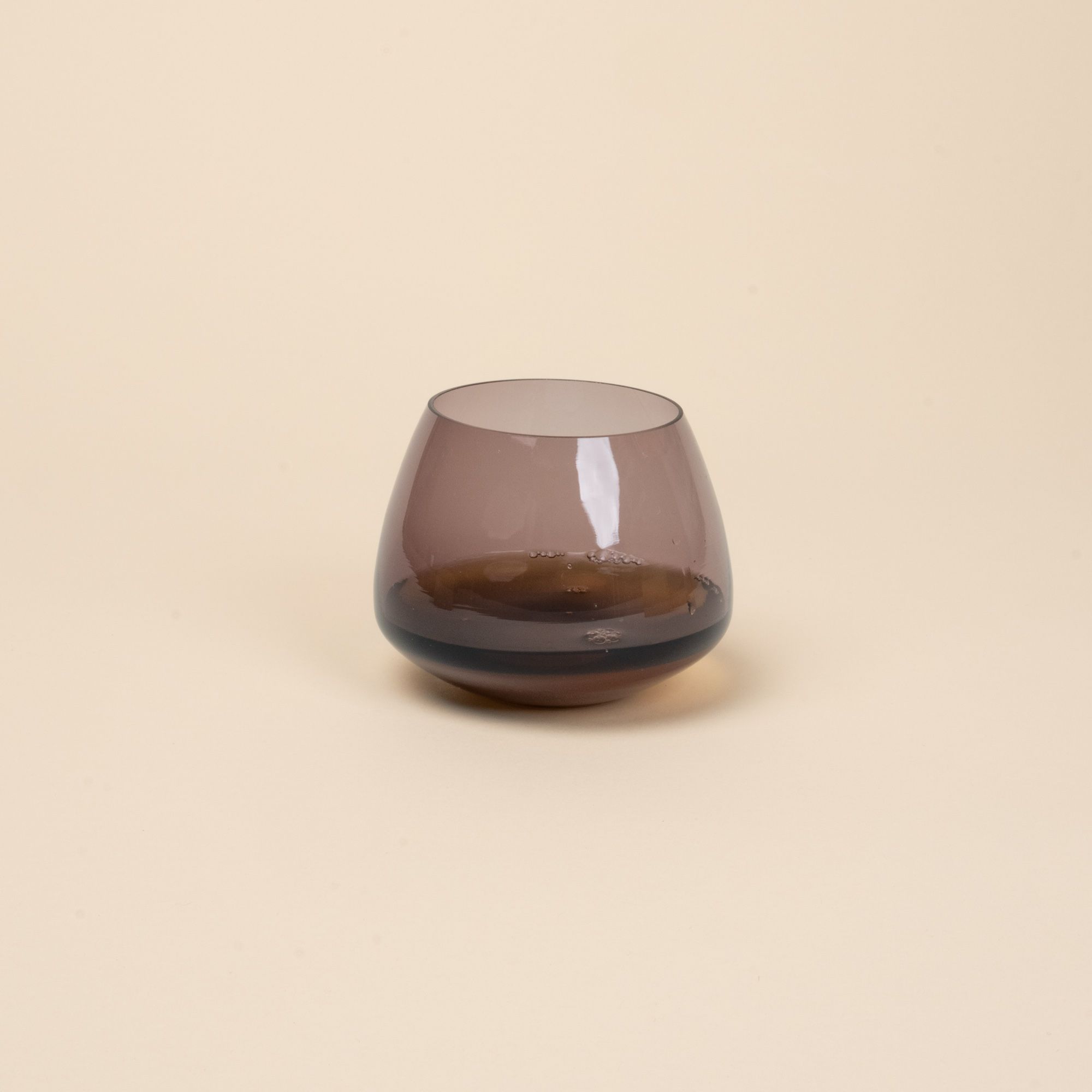 Muted purple glass whiskey snifter with a rounded base, with whiskey inside