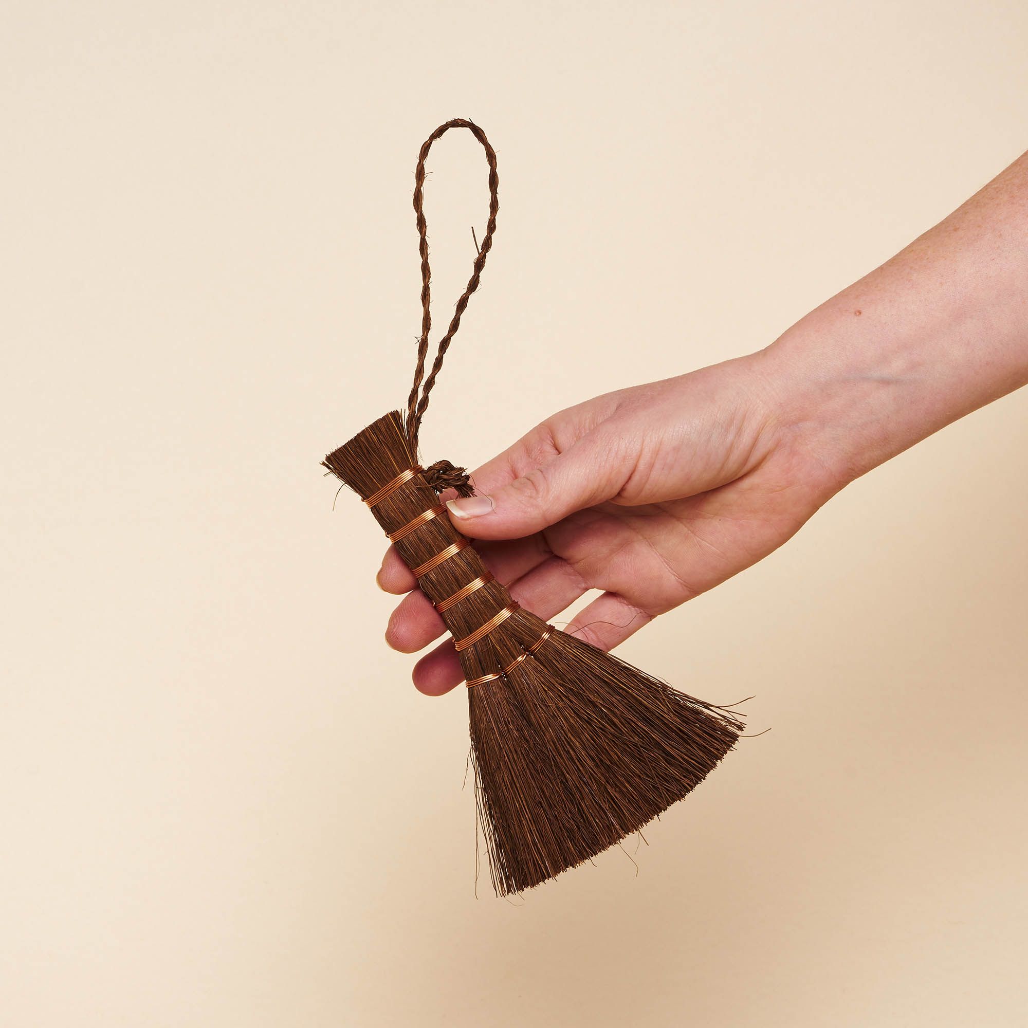 A small hand broom with a palm wooden handle