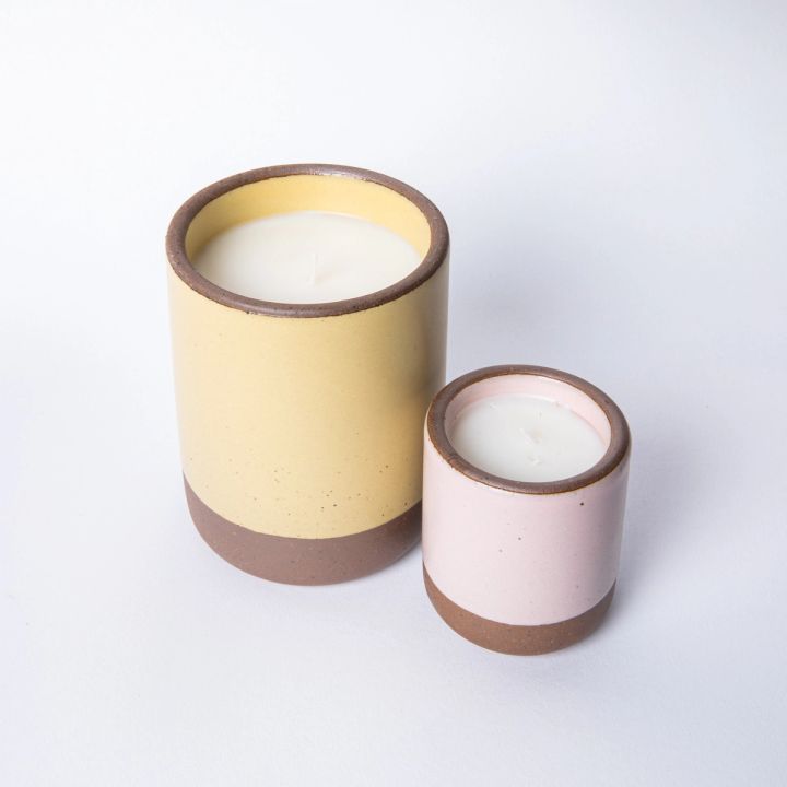 A large and small ceramic vessel in soft butter yellow and soft light pink color with candles inside