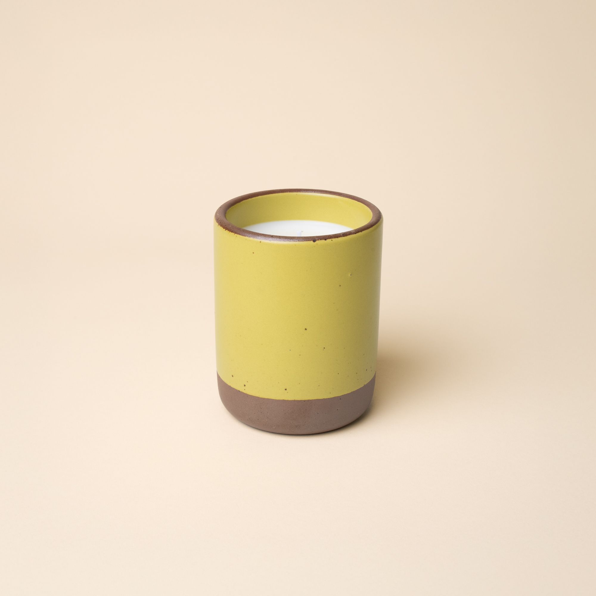 Large ceramic vessel in a zesty yellow color with candle inside.