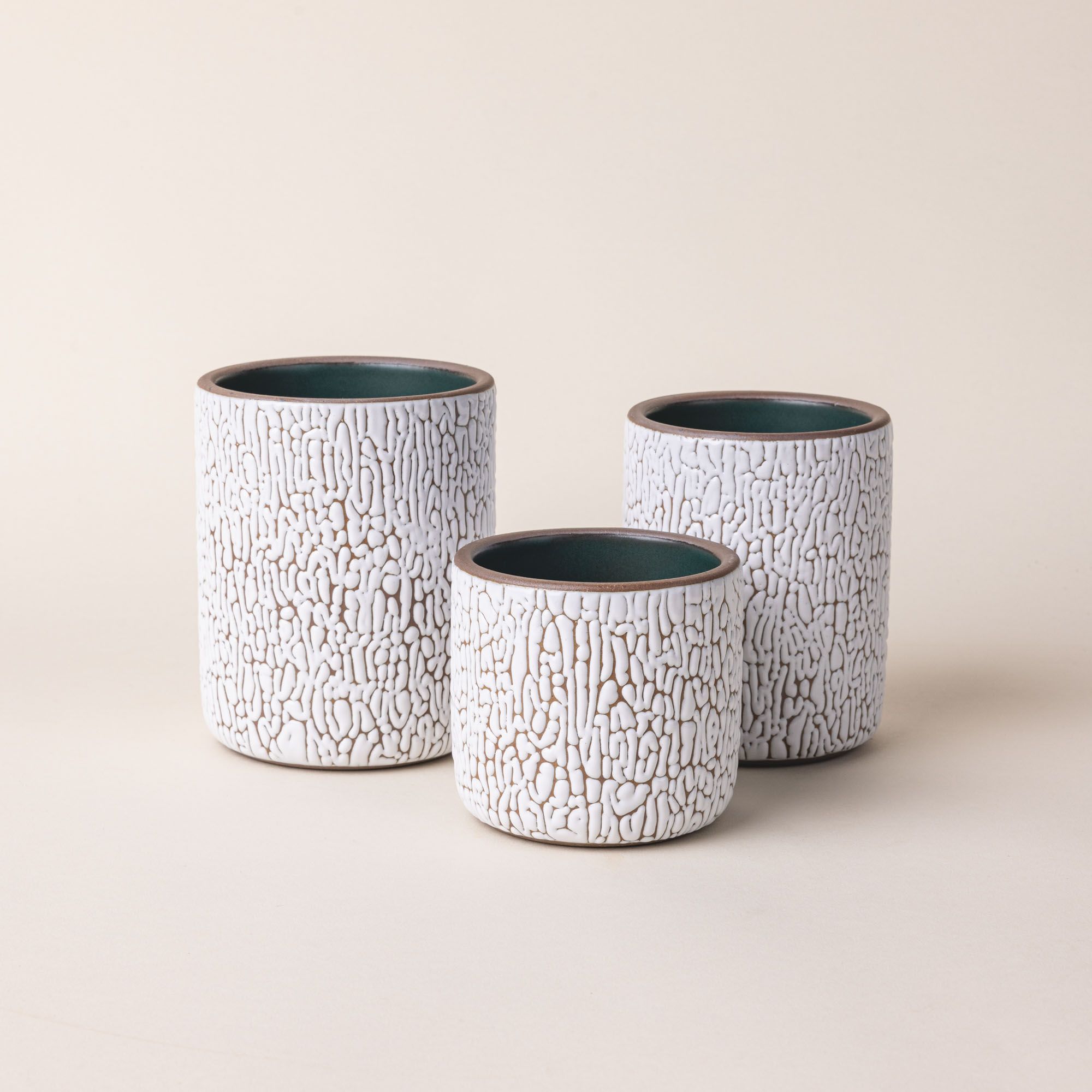 Three white ceramic vessels in Small, Medium, and Big with cracked texture and the interior being dark teal