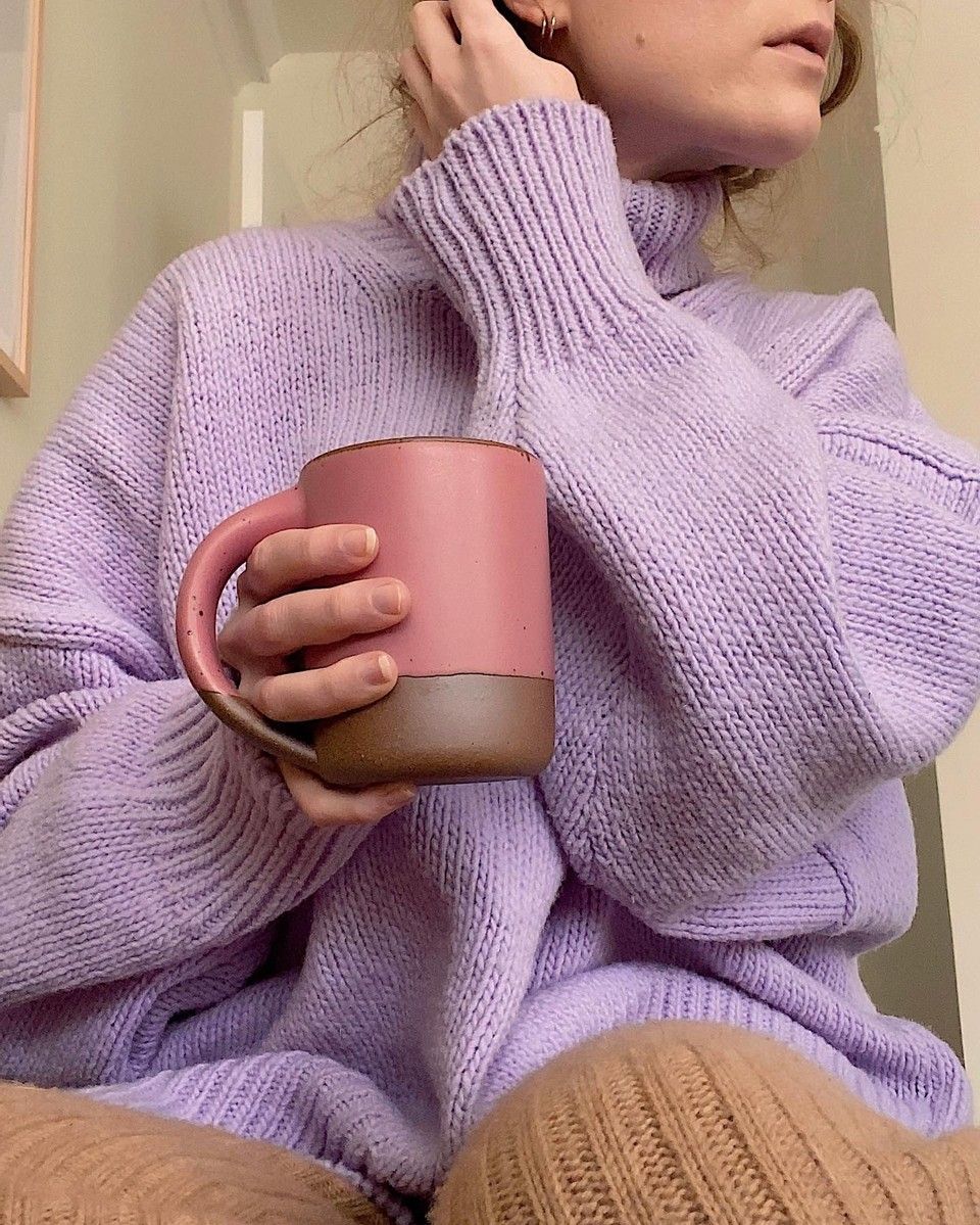 A woman in a chunky purple sweater holds a hot pink East Fork Mug in Rococo. A very cozy vibe.