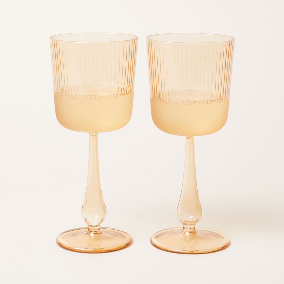 A pair of stemmed wine glasses made of pale yellow glass
