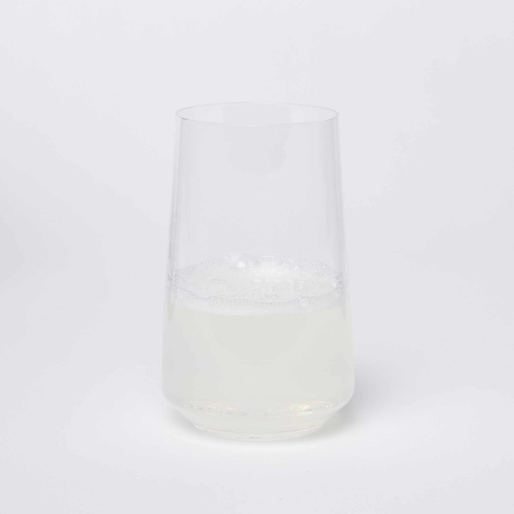 A clear round glass half full of a semi-opaque beverage