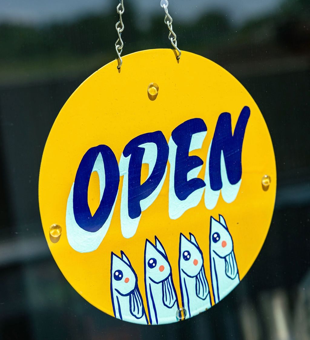A yellow and blue open sign with illustrations of fish