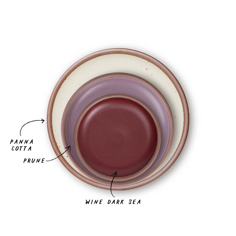 A stack of 3 plates in Dinner, Side, and Cake sizes in a warm off-white, soft mauve purple, and plum colors.