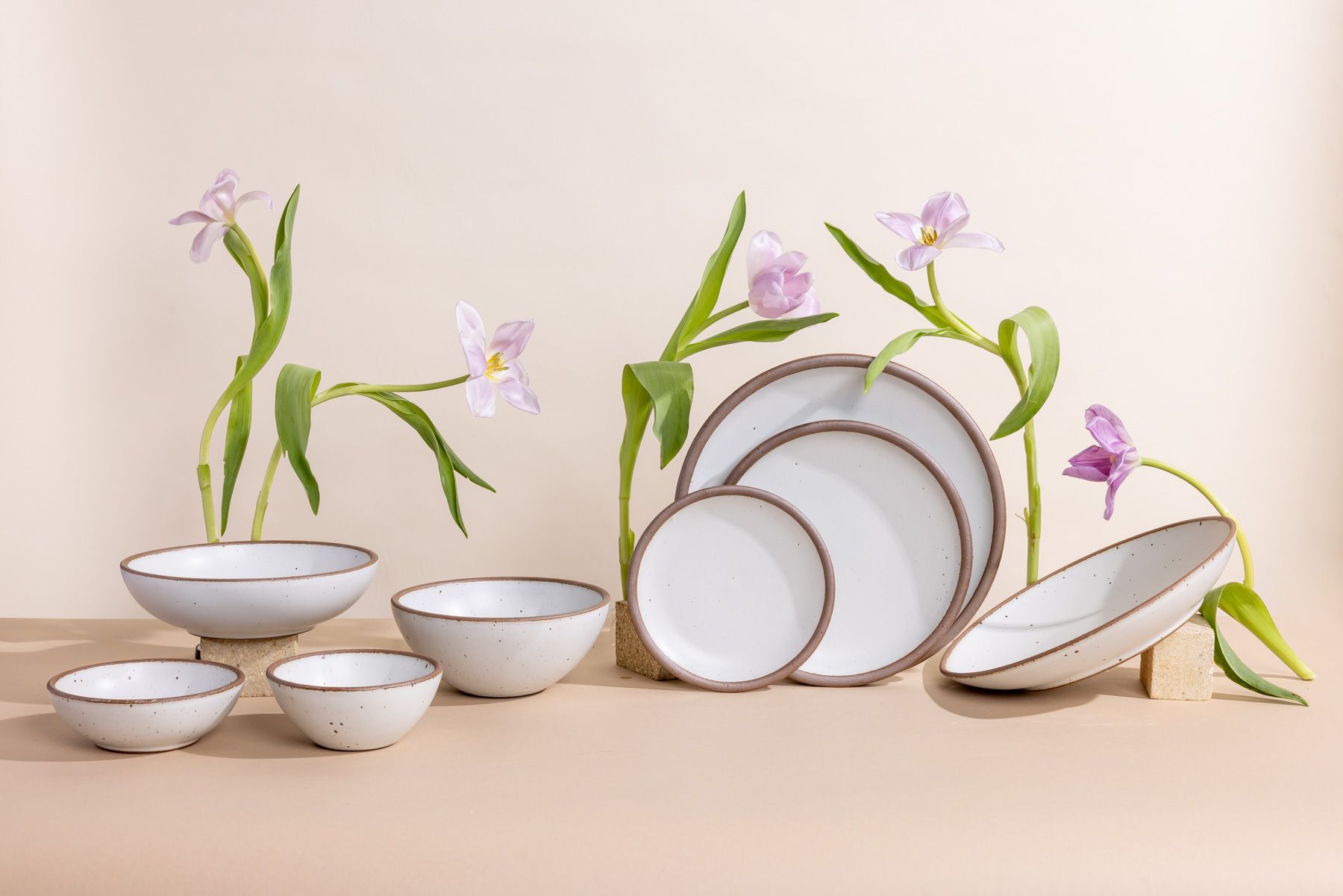 Artfully arranged white ceramic dinnerware styled with soft purple stems.