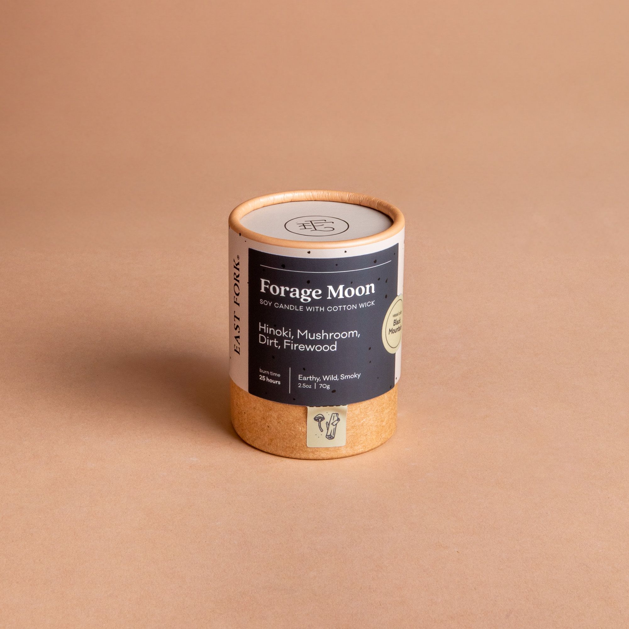 Small cardboard packaging tube with a candle inside with branding on it that says 'Forage Moon'