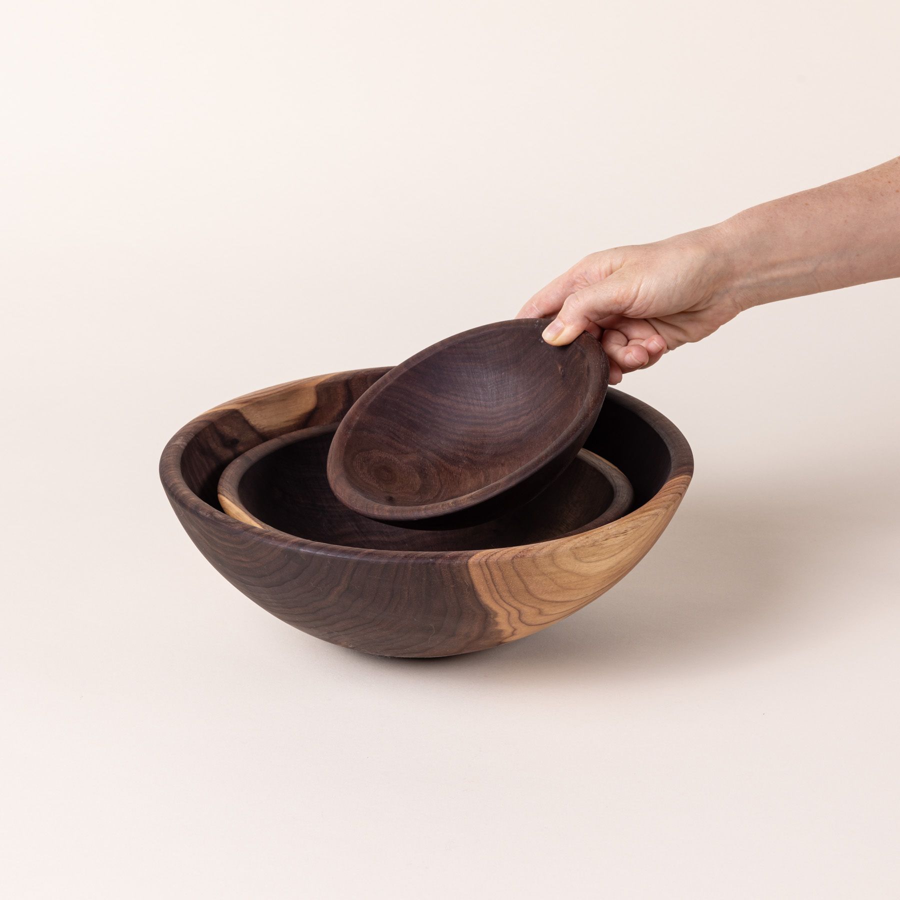 3 round walnut bowls nesting together in small, medium, and large sizes.