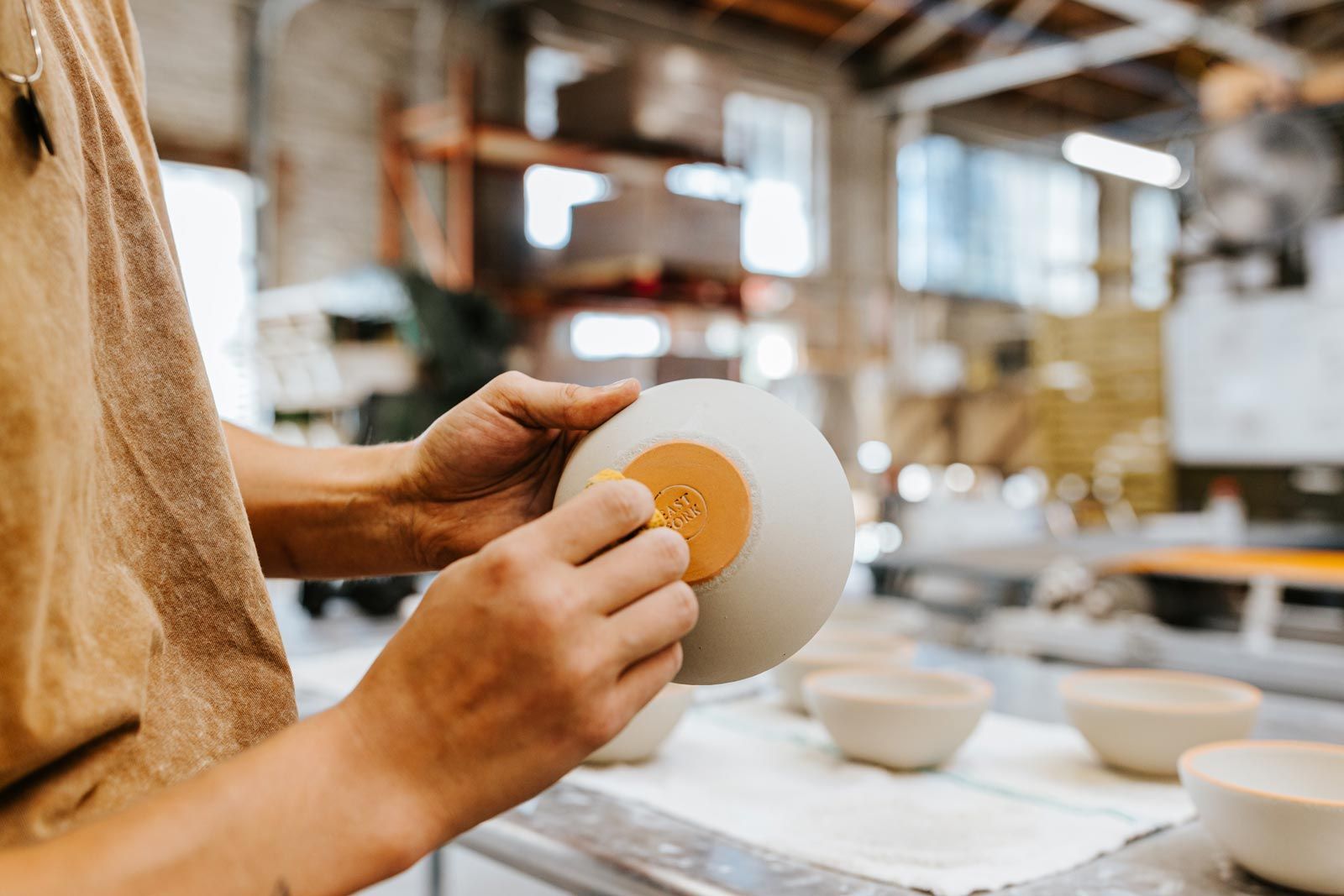 Hand washing glaze off the bottom of bowl