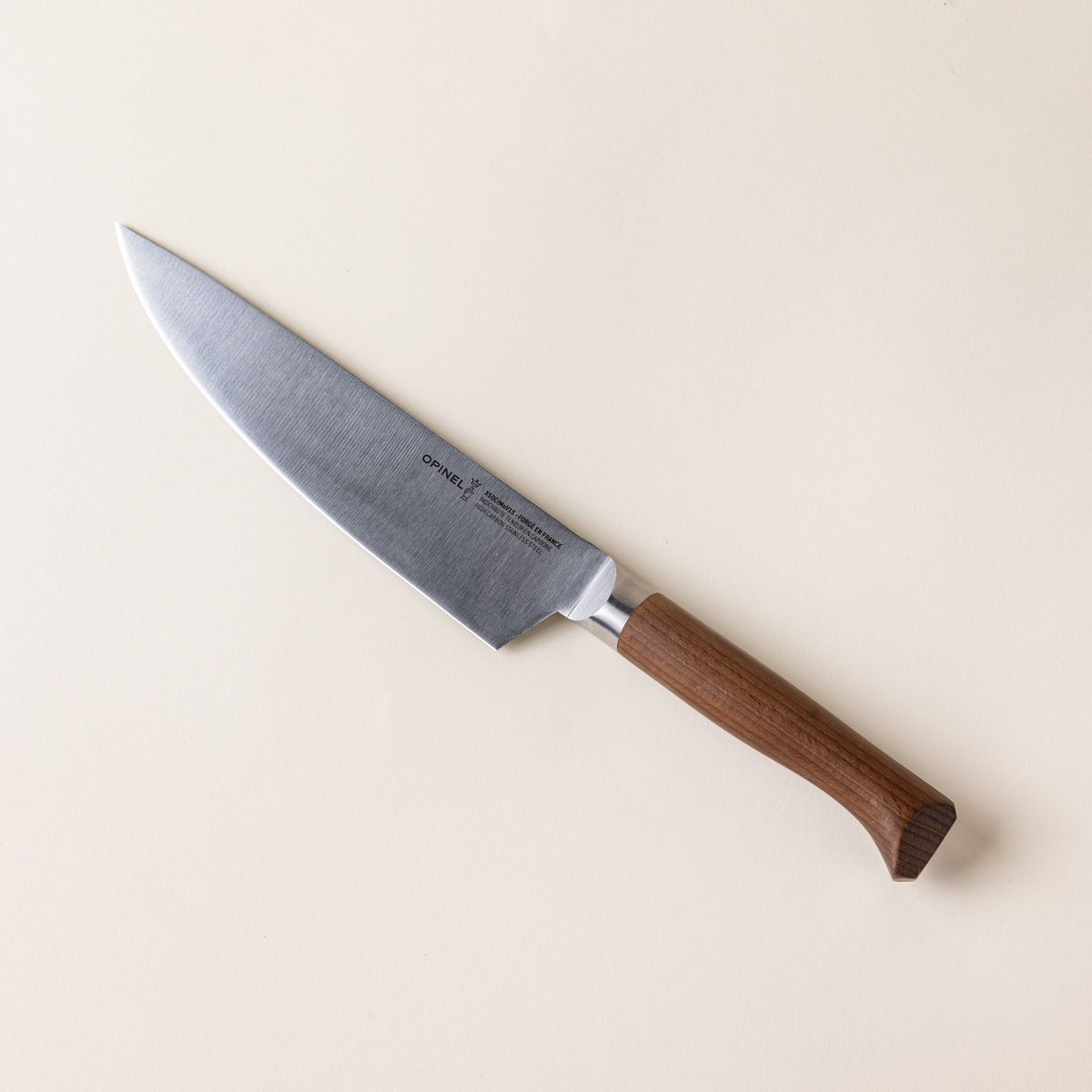 A chef's knife with a sharp steel blade with a beveled dark wood handle