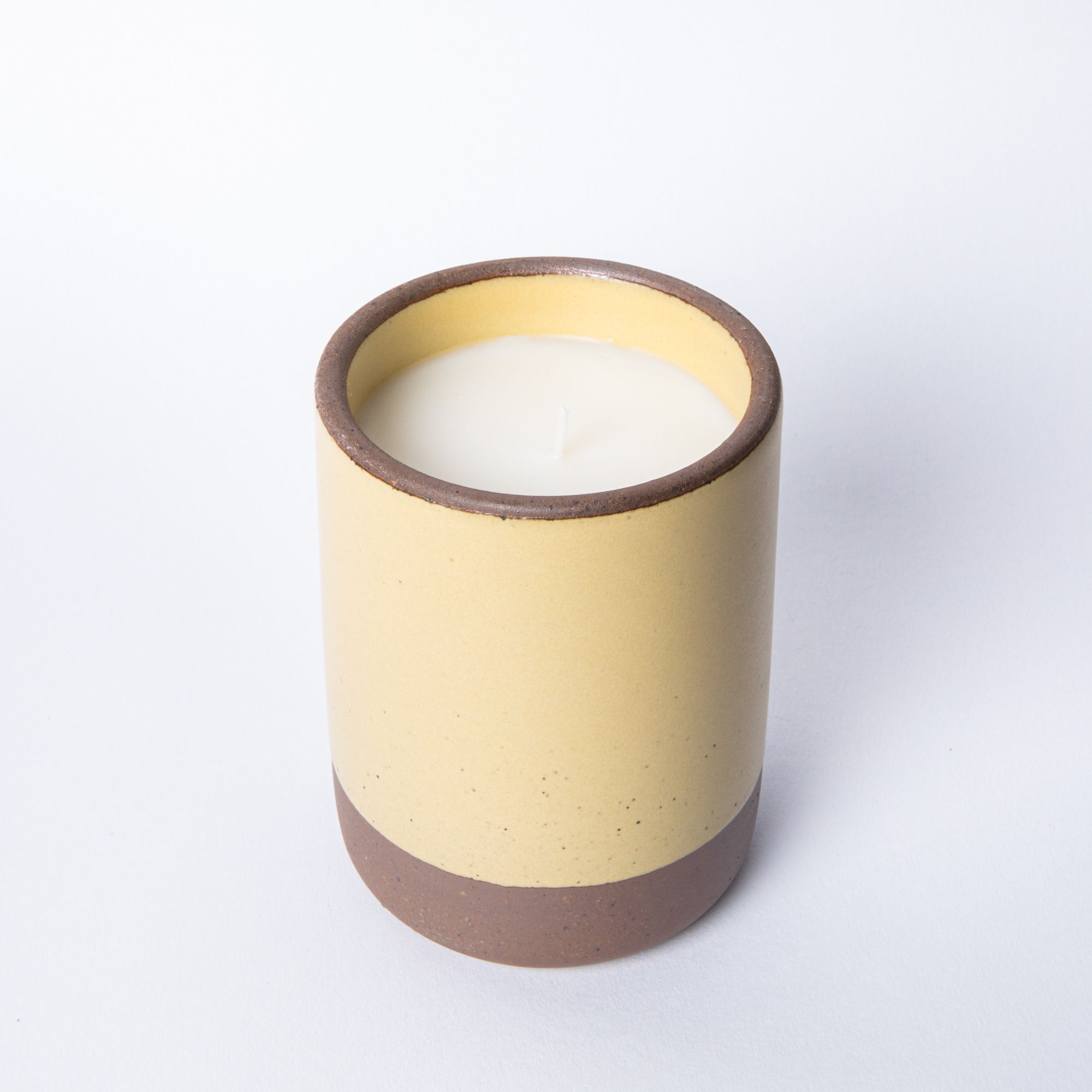Large ceramic vessel in soft butter yellow color with candle inside