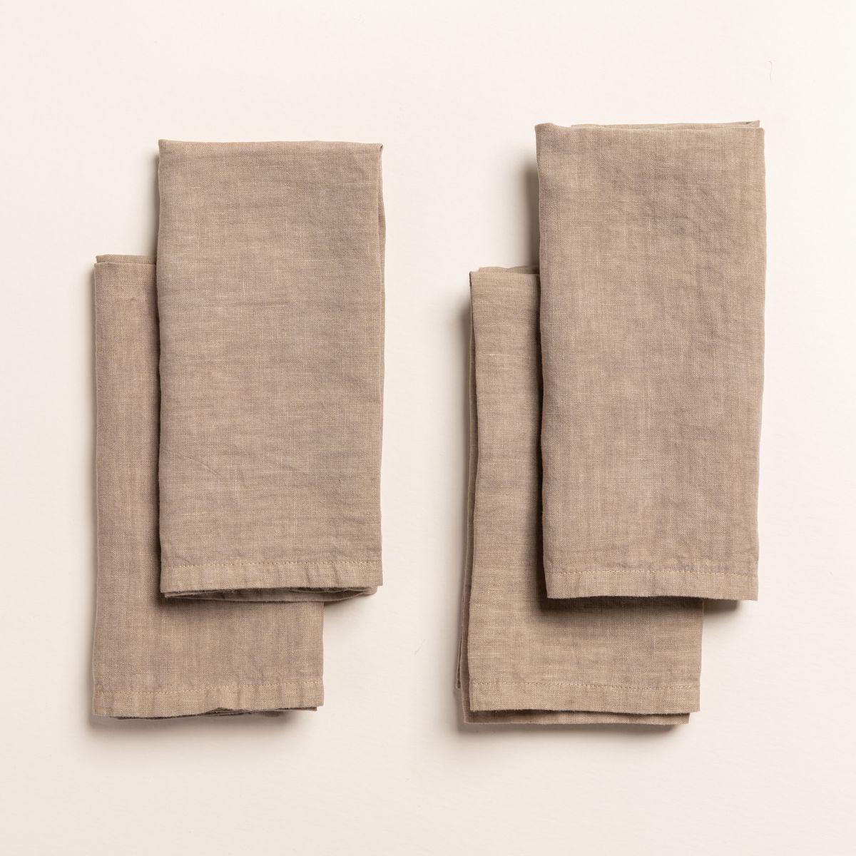 4 folded linen napkins in a natural color