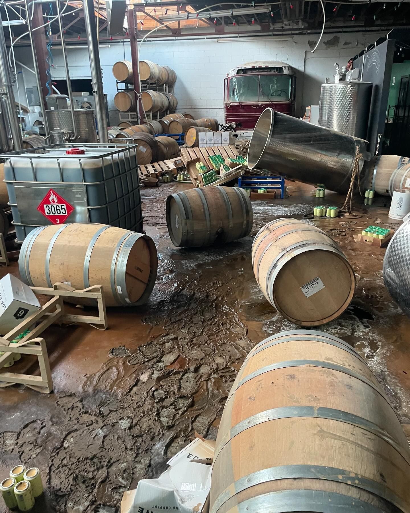 A distillery with barrels and equipment knocked over and debris on the floor.