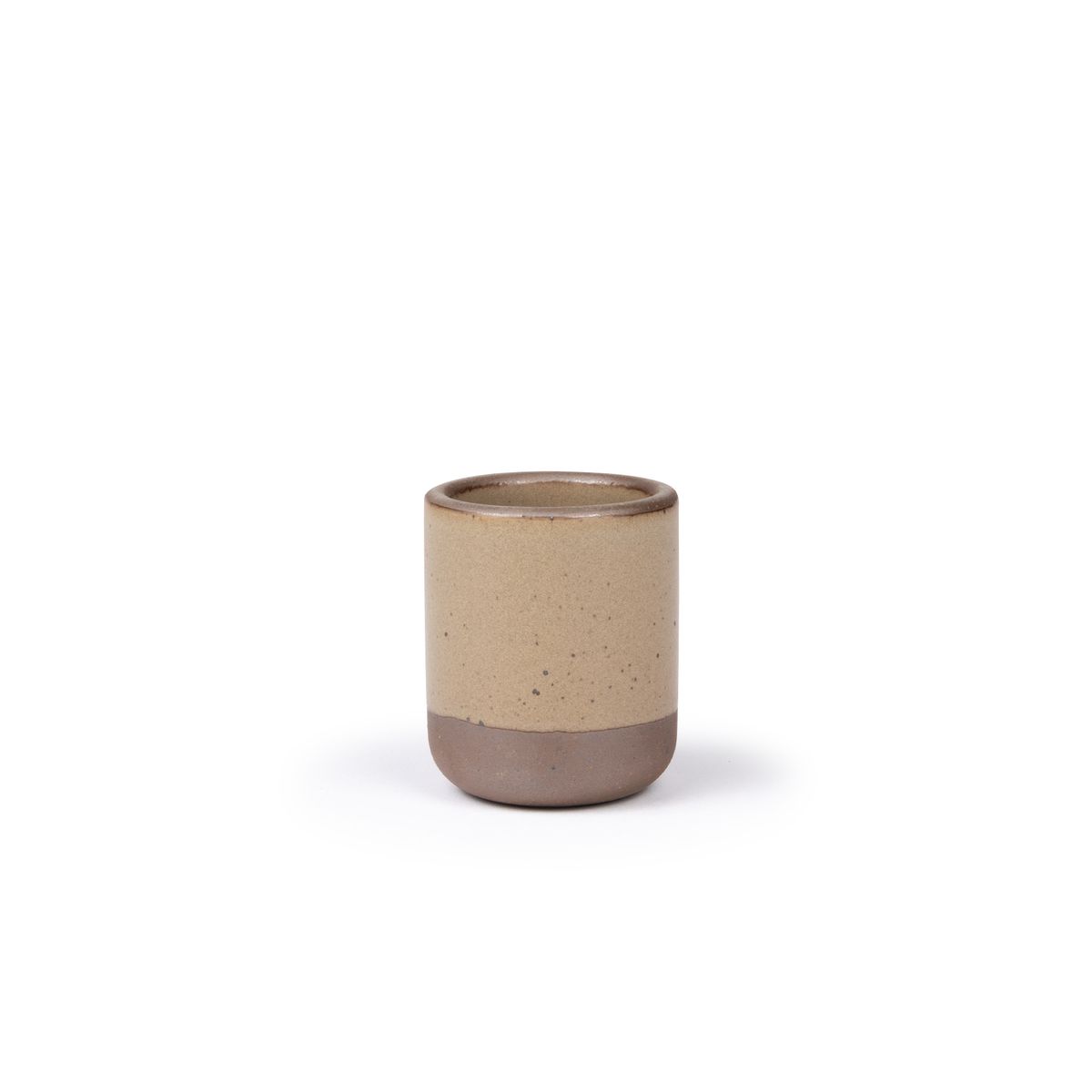 A small, short ceramic mug cup in a warm pale brown color featuring iron speckles and unglazed rim and bottom base.